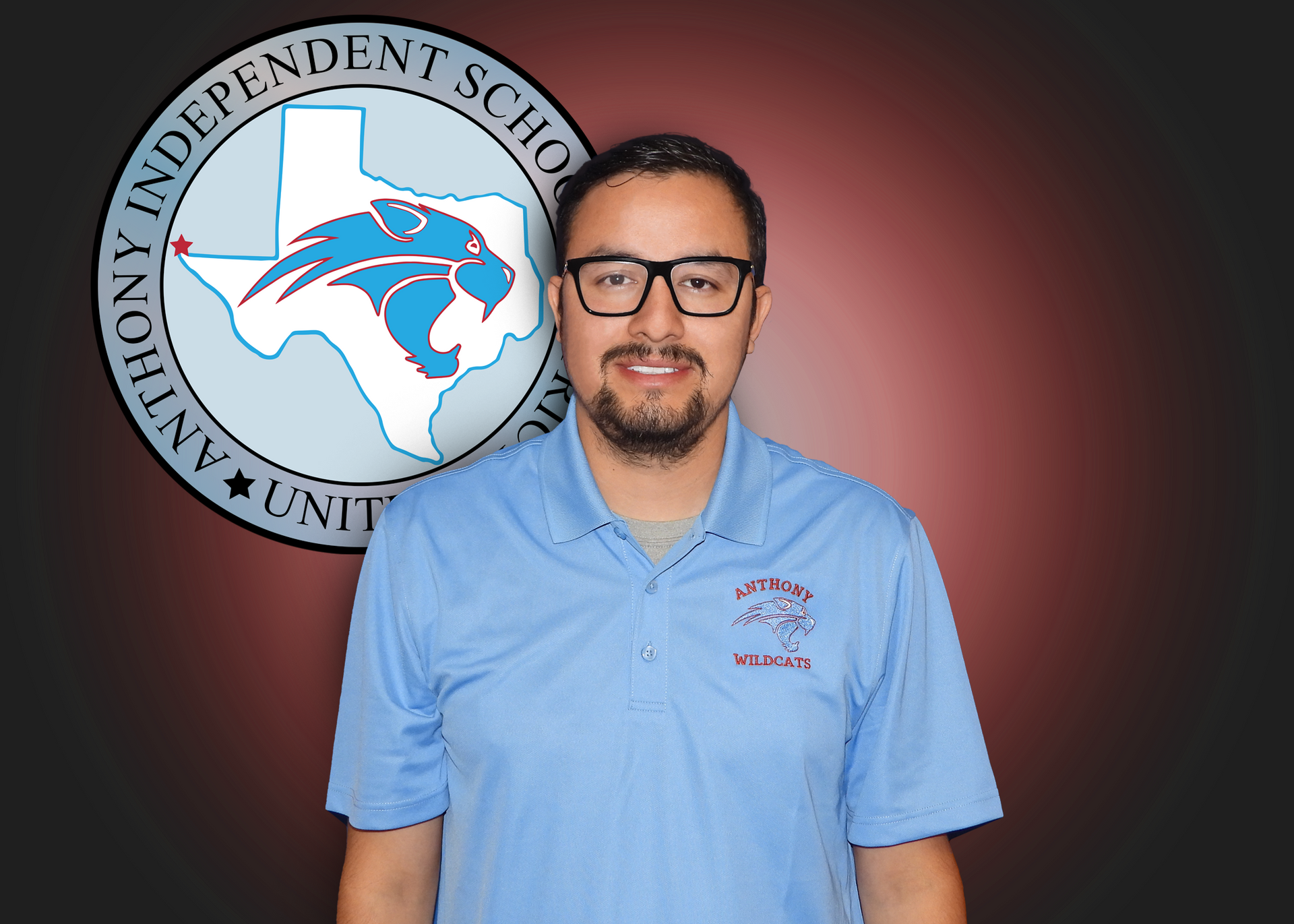 A man wearing glasses and a blue shirt is standing in front of an independent school logo.