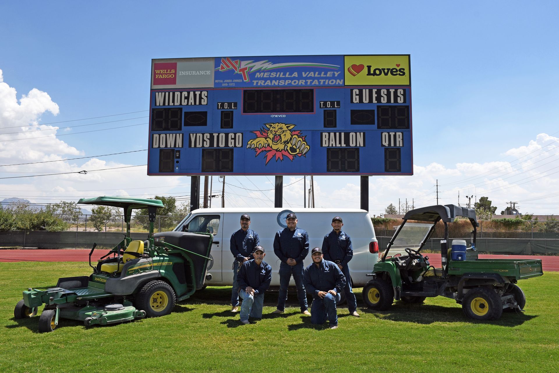 Groundskeeping team posing in front of their utility van, lawn mower and tractor