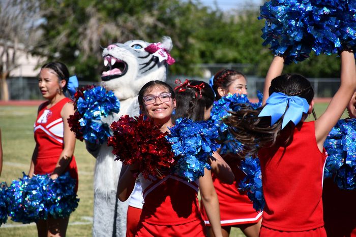 Anthony Middle School cheerleader holds her red and blue pom-poms a smiles at crowd