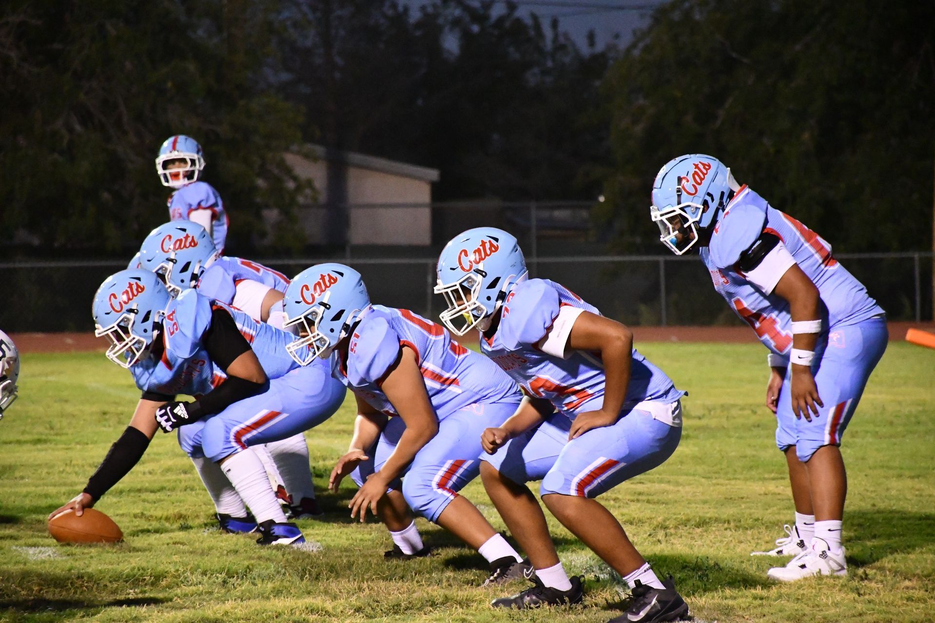 Anthony football athletes huddle and place football on floor.