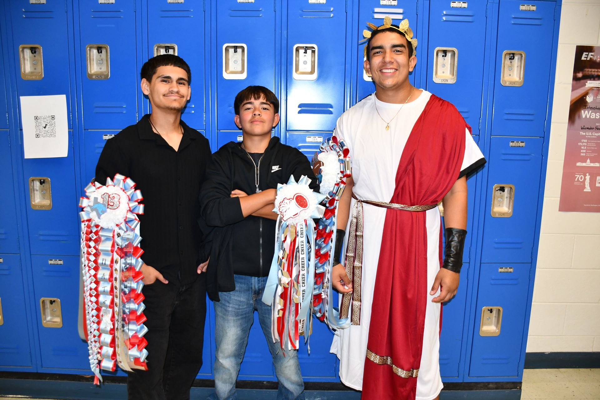 Three students smile for the camera. One is wearing a toga for homecoming. They're all wearing mums.