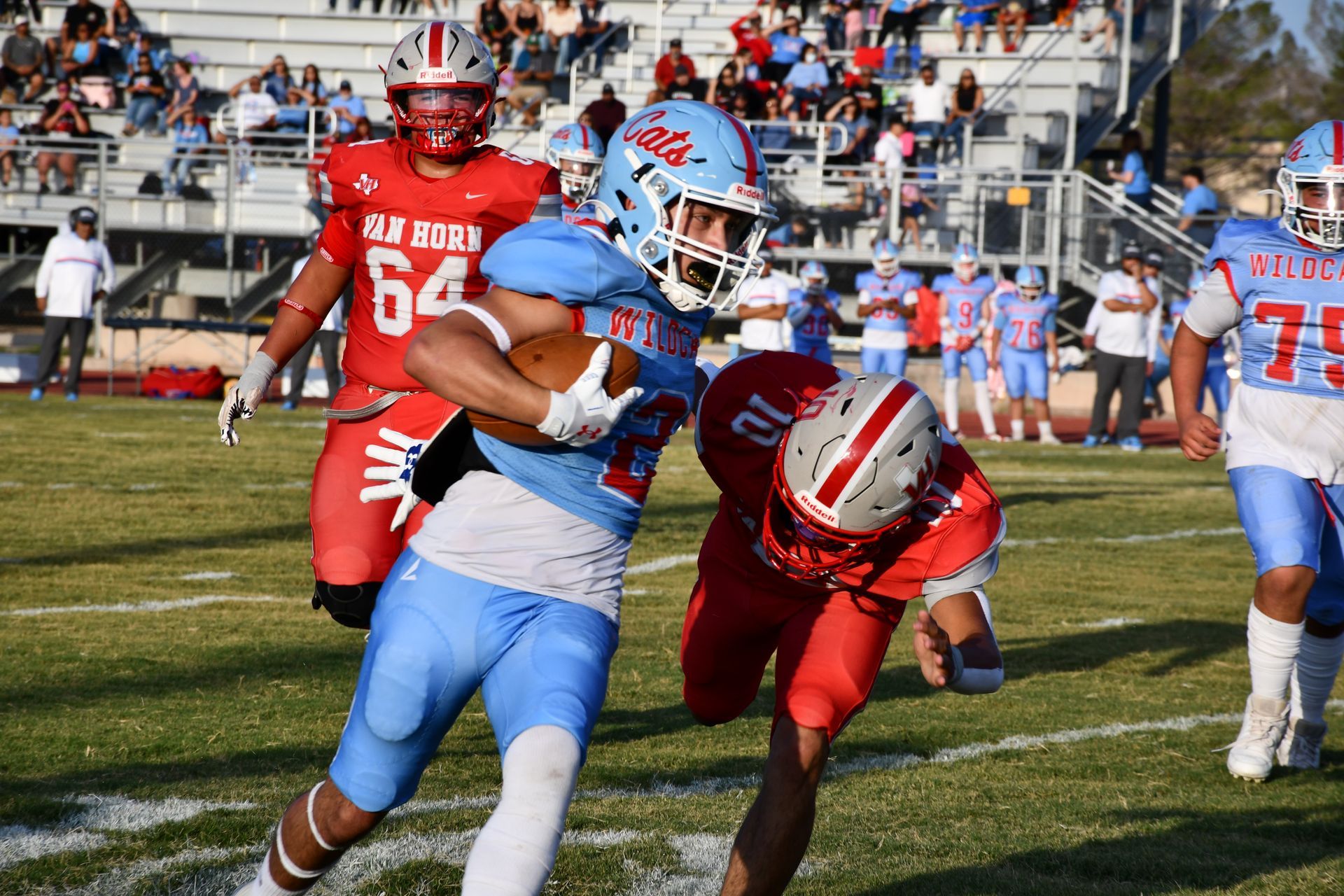 Fotball player runs the ball while opposing team tries to tackle him.