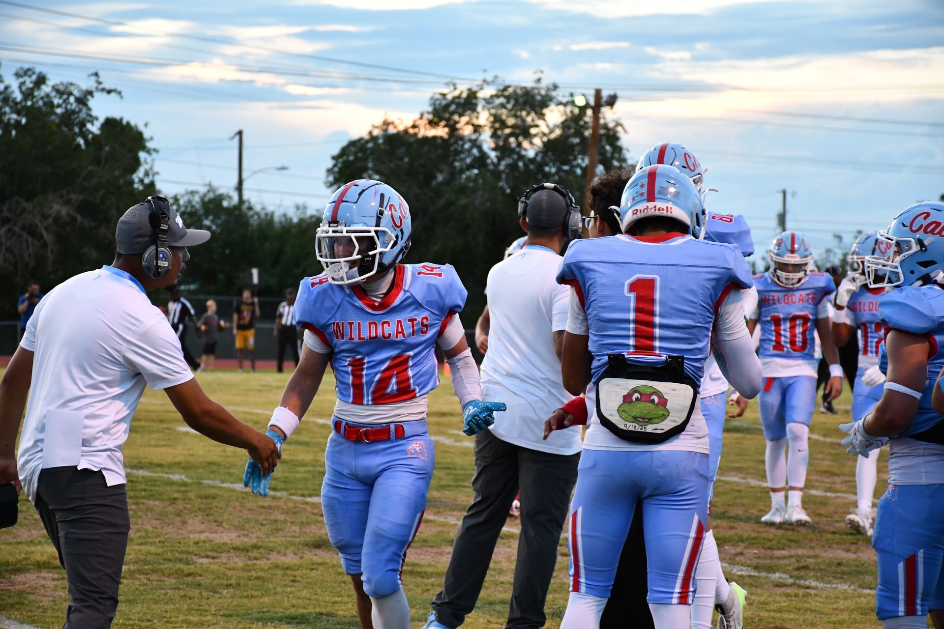 Football player shakes the hand of coach on the sideline