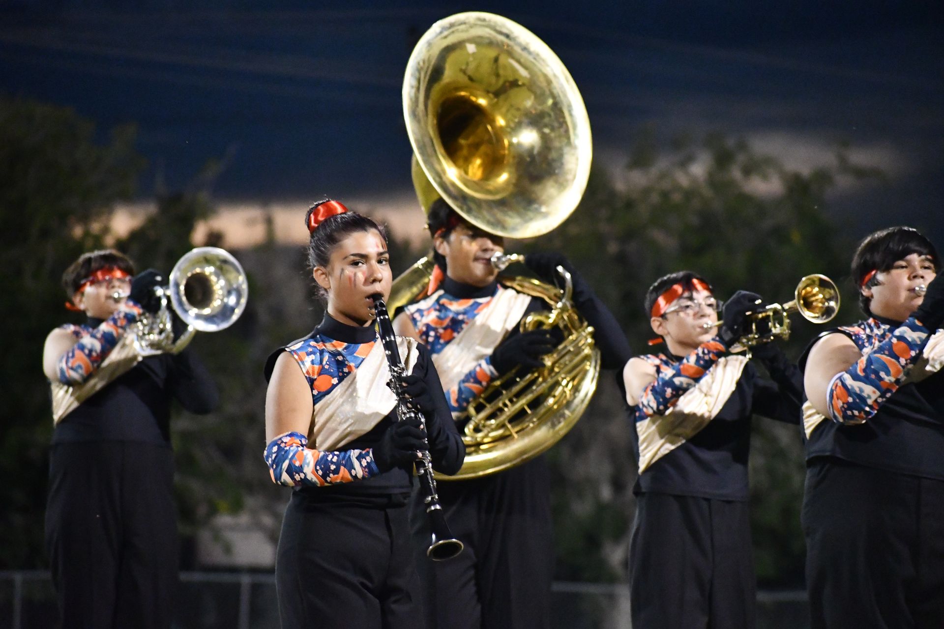 Female student plays tuba on football field during halftime of the homecoming game. Student is wearing Asian-isnpired uniform.
