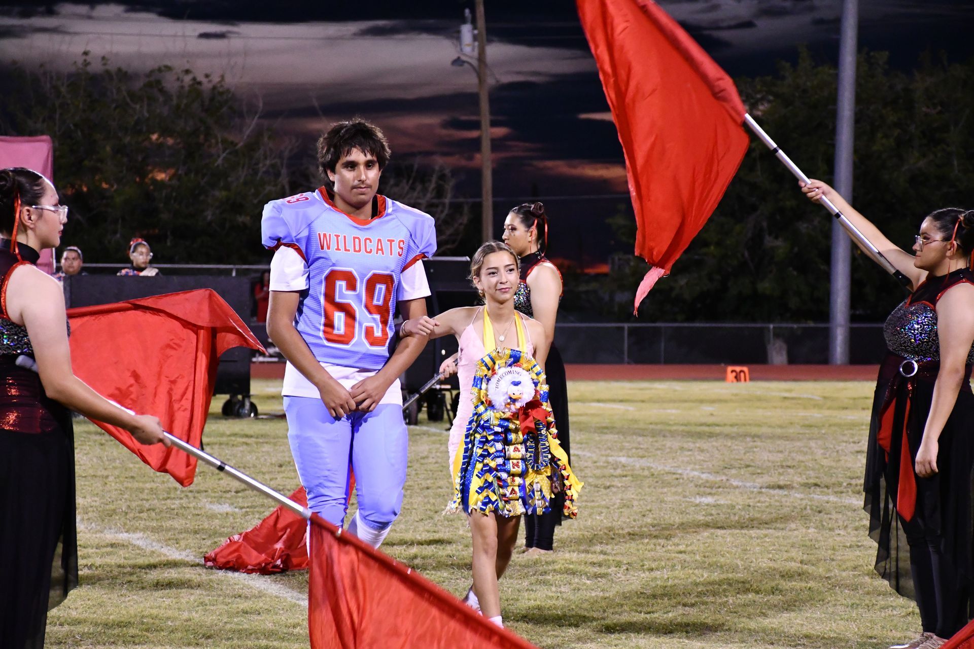 Female student is escorted by football player during homecoming halftime show