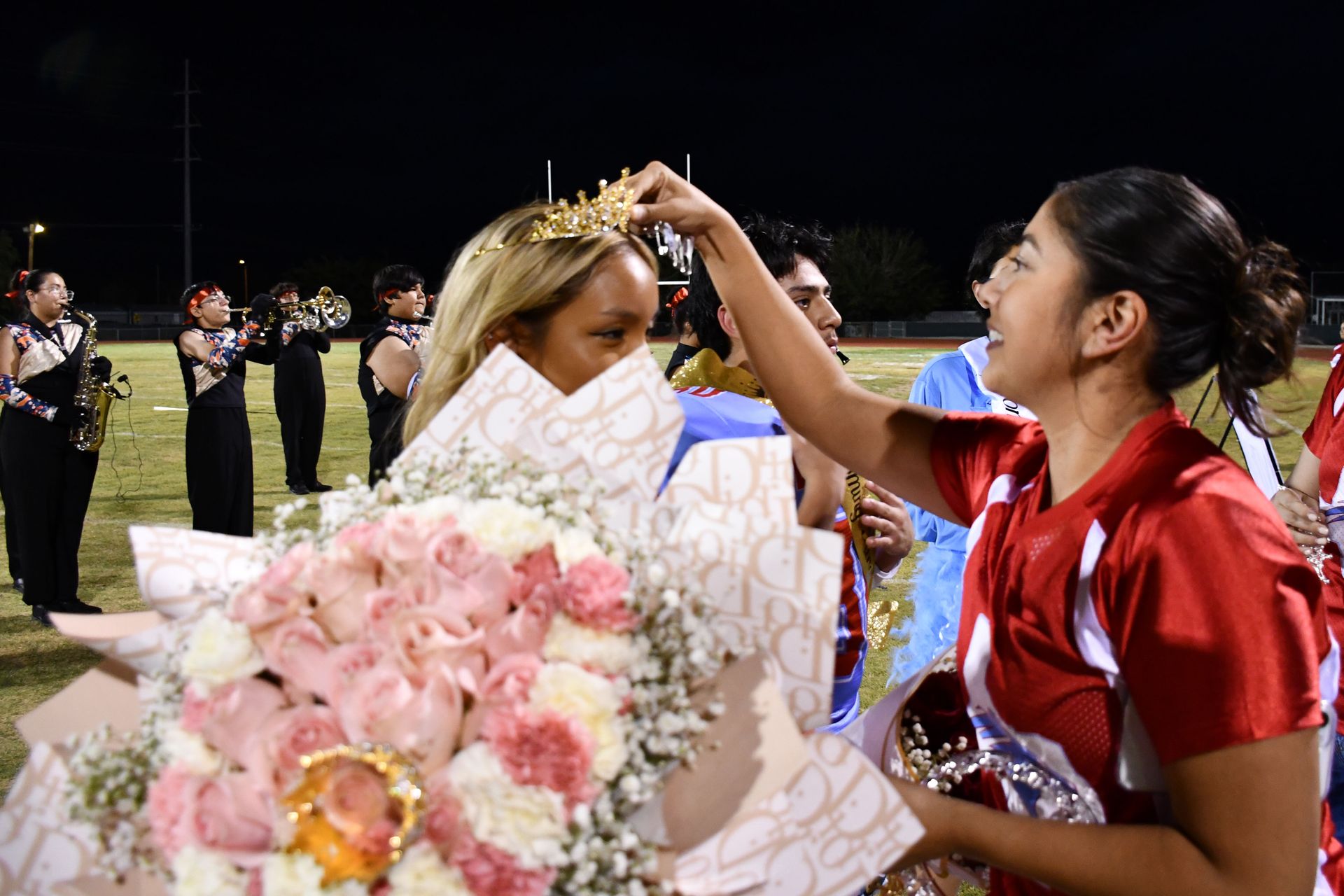 Student holds flowers as employee crowns her Homecoming Queen