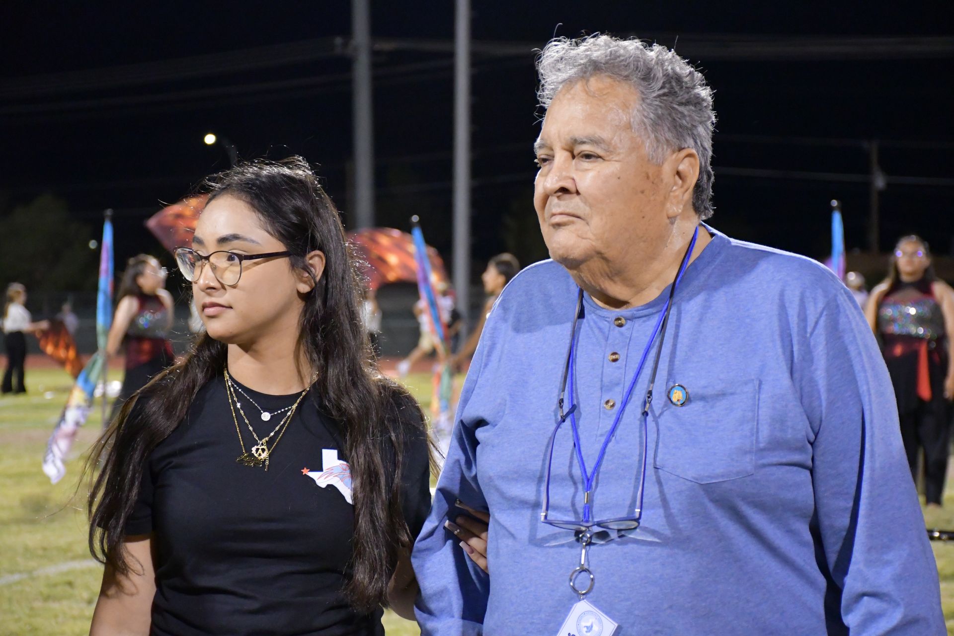 Female student wearing glasses and man wearing blue shirt look to the side.