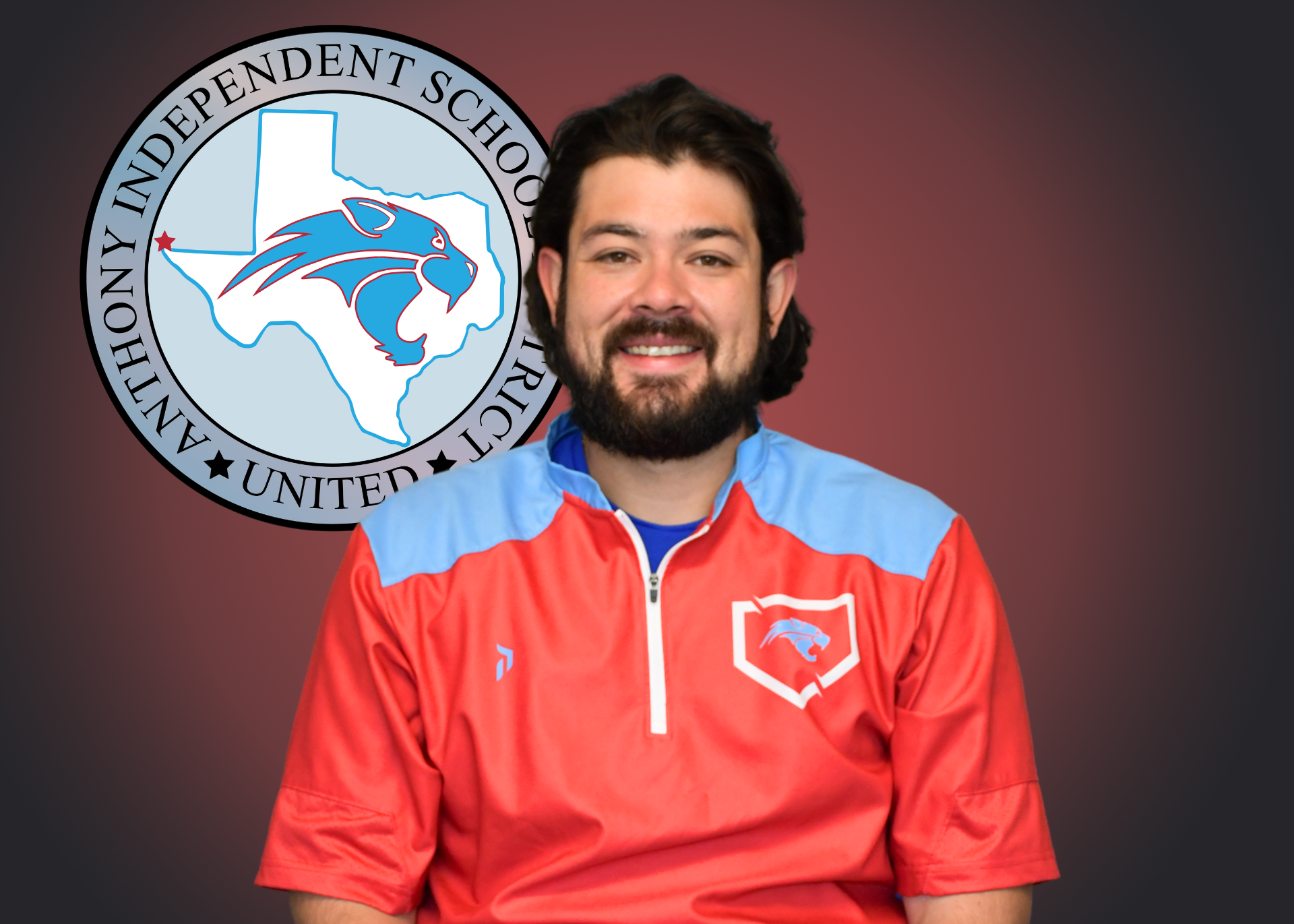 Man wearing red shirt stands in front of independent school district logo
