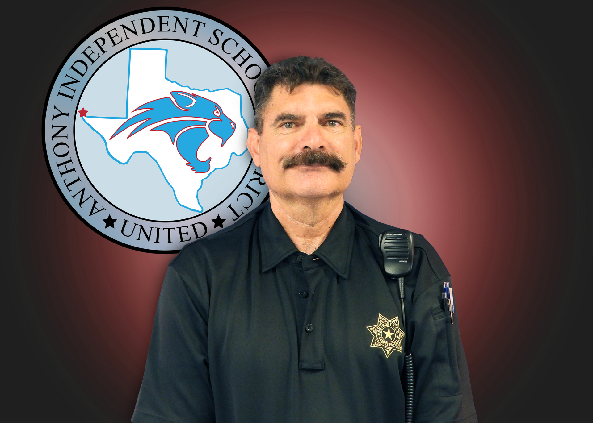 Man wearing black shirt stands in front of Anthony ISD logo.