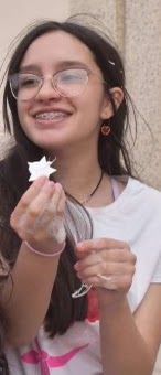 A girl wearing glasses and braces is holding a flower in her hand.