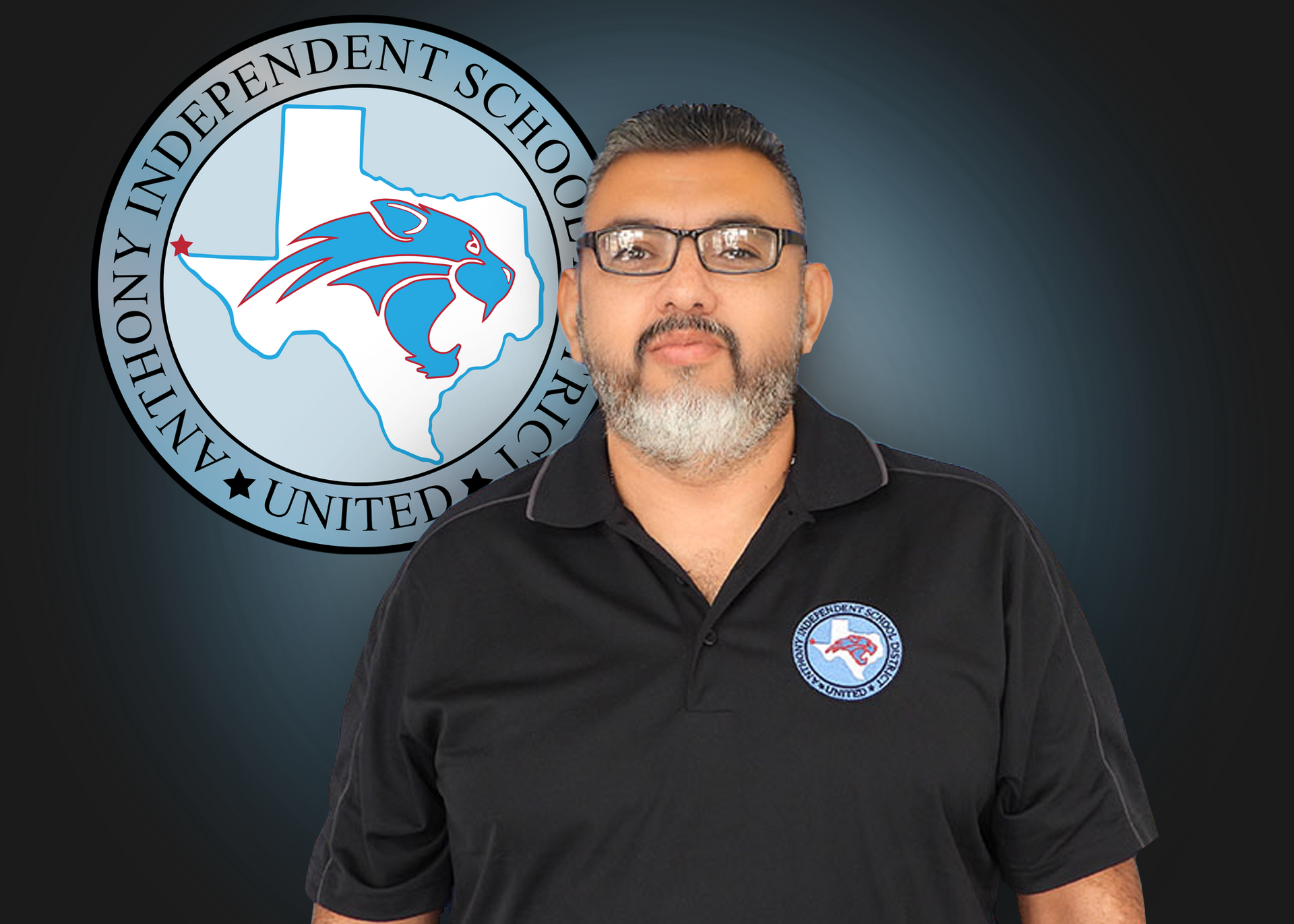 A man wearing glasses and a black shirt is standing in front of an independent school district logo.