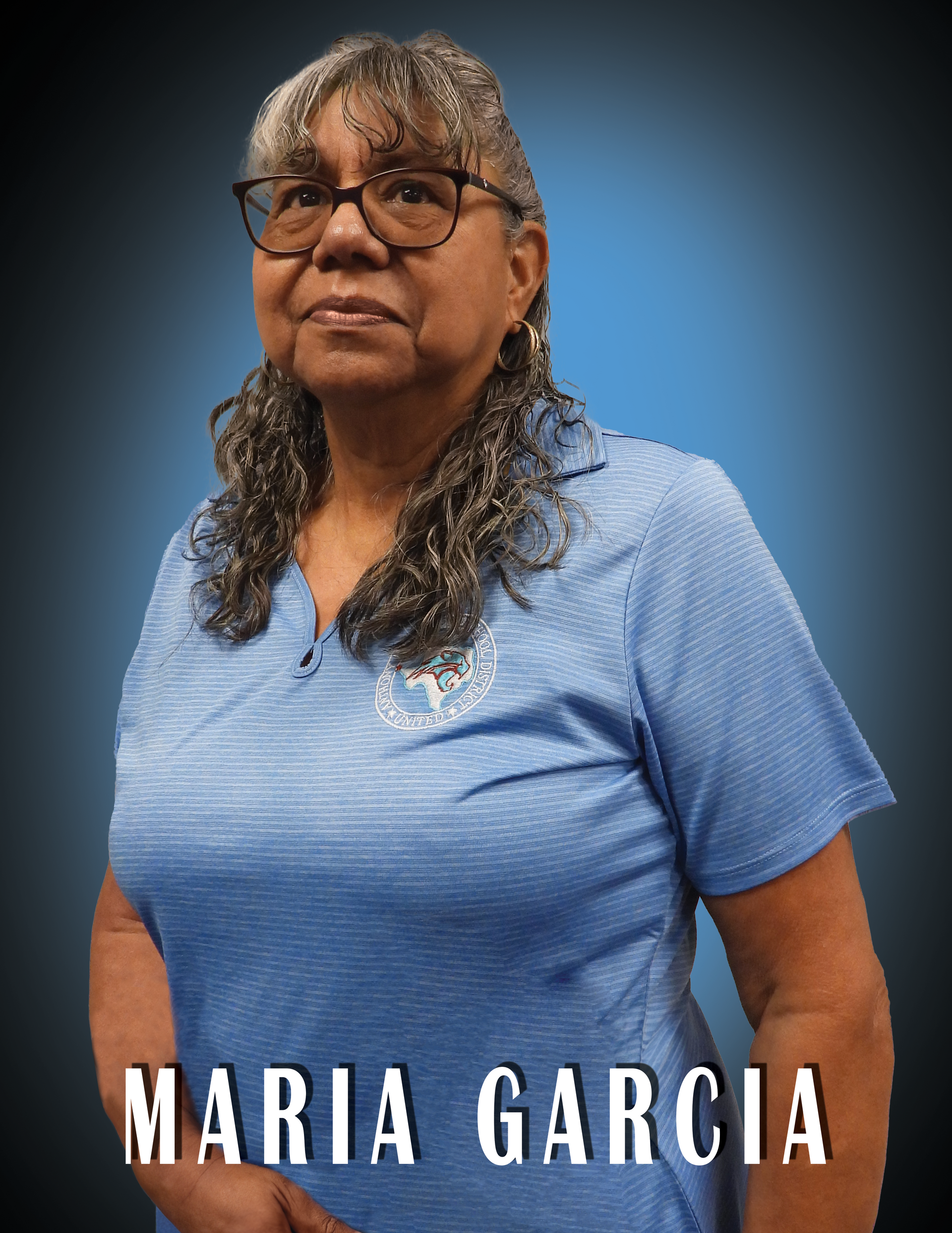 Trustee Maria Garcia wearing a blue shirt is standing in front of a blue background.
