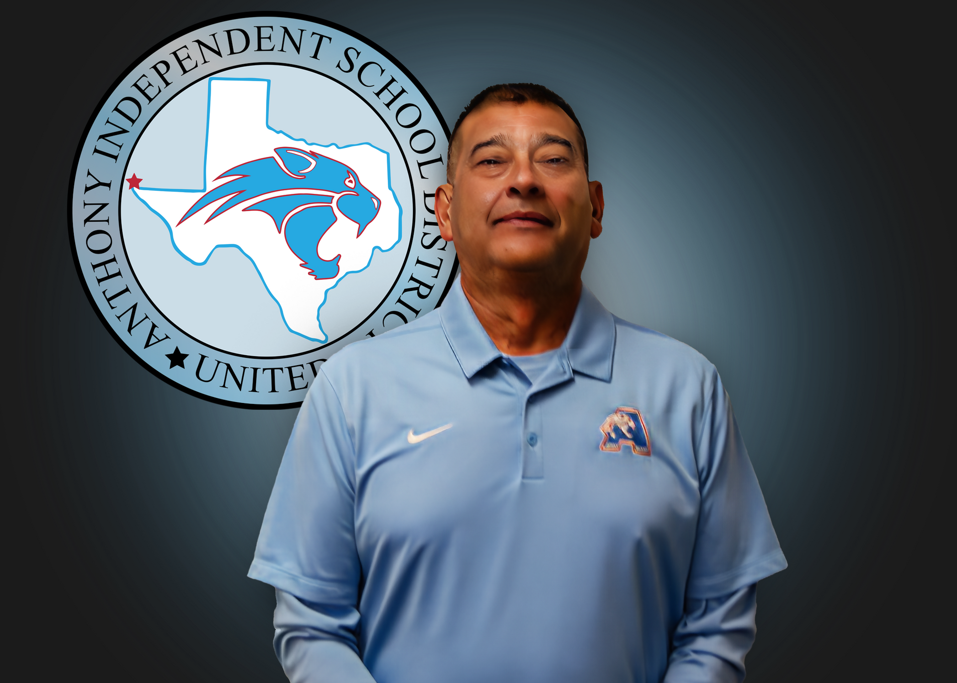 A man in a blue shirt is standing in front of an independent school district logo.