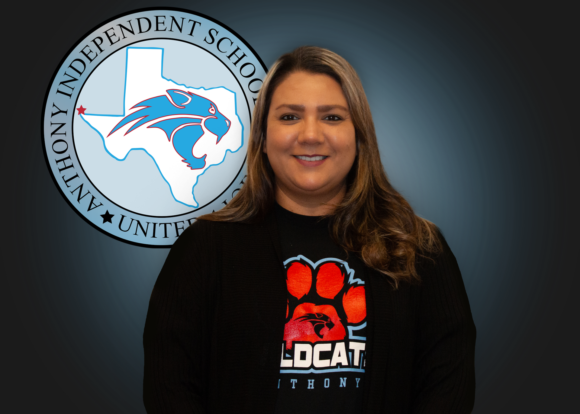 A woman wearing a black shirt with a paw print on it is standing in front of a logo for anthony independent school