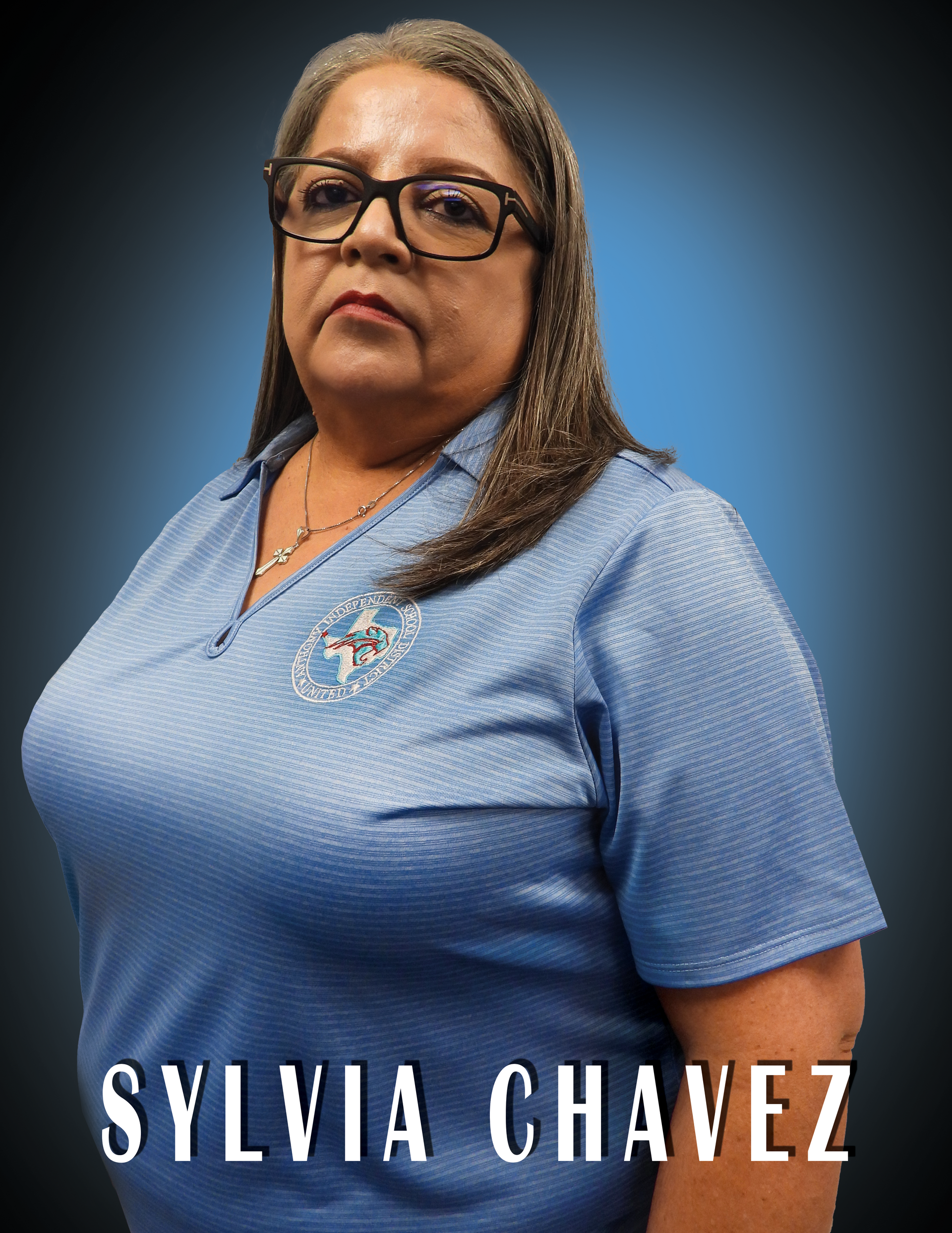 Secretary Sylvia Chavez wearing a blue shirt standing in front of a blue background.