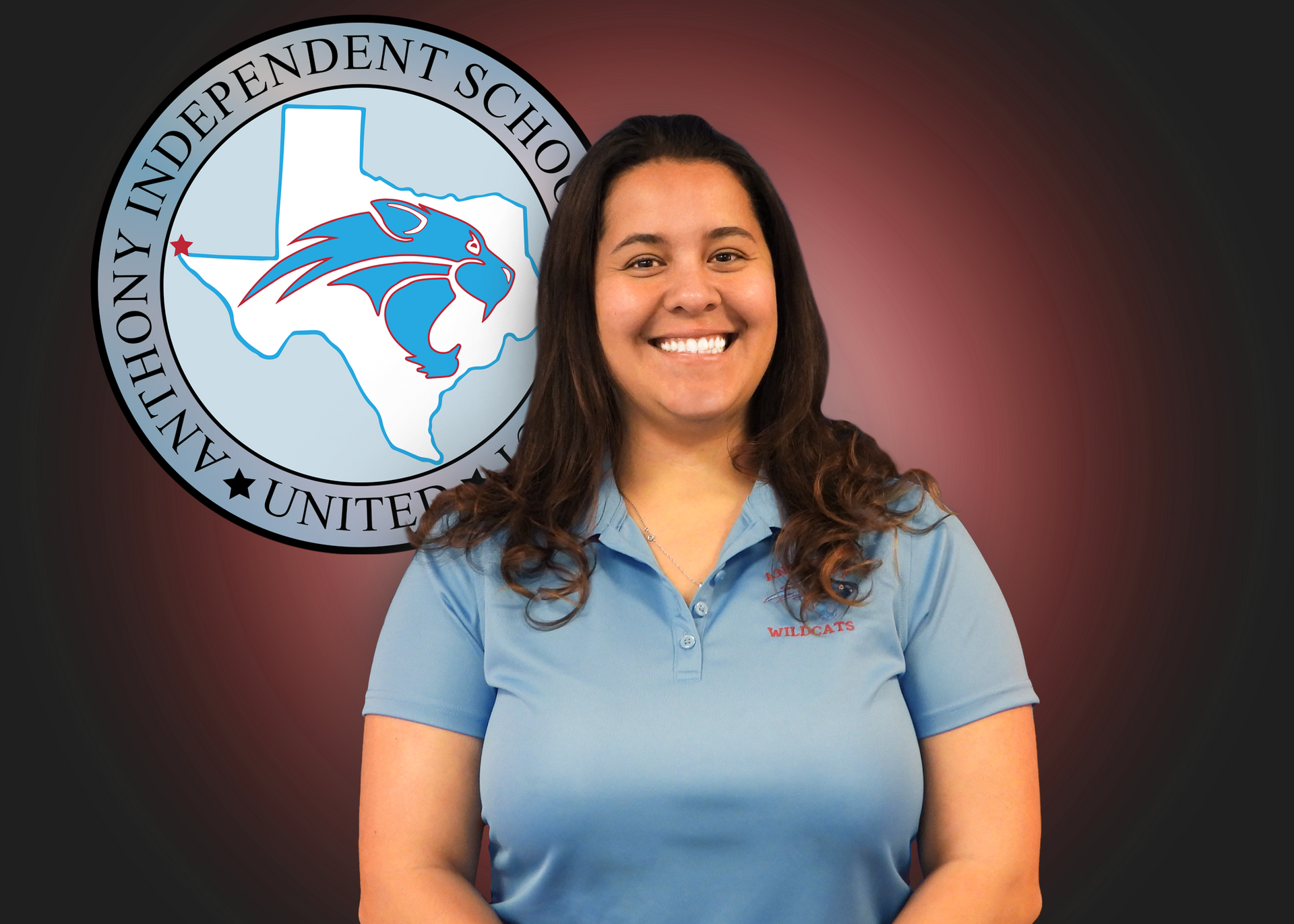 A woman in a blue shirt is smiling in front of a logo for anthony independent school