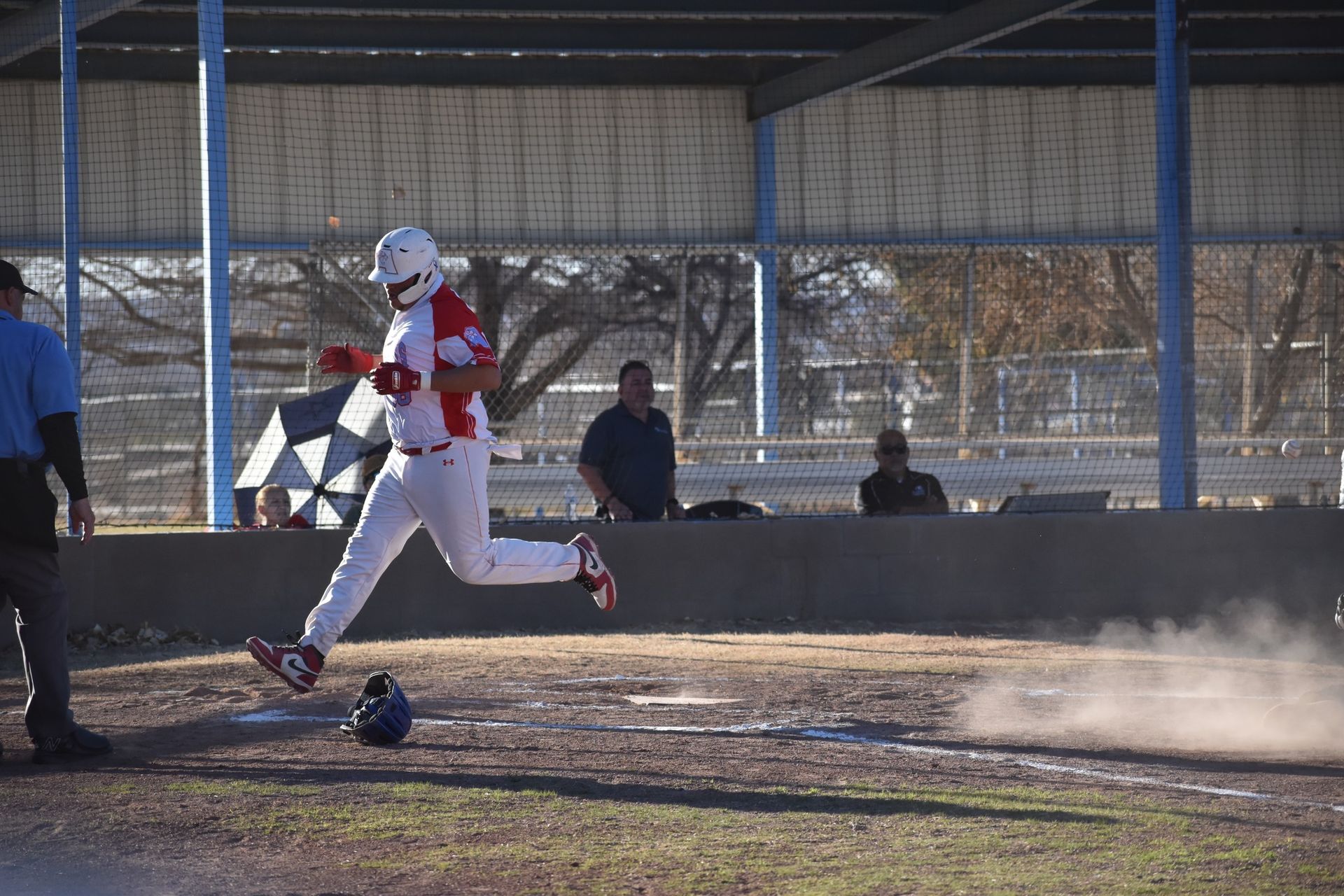 Anthony baseball player runs over the home plate while leaving a cloud of dust behind him. 
