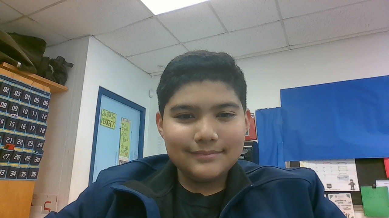 A young boy in a blue jacket is smiling for the camera