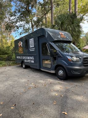 Dark blue mobile grooming van parked outdoors. QR code and grooming business name on the side.