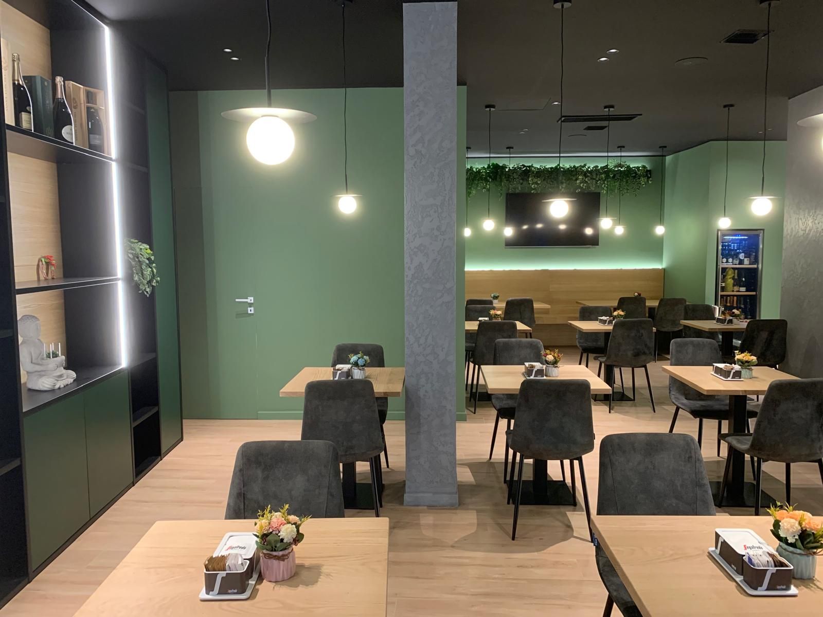 Un ristorante con tavoli e sedie e una parete verde.