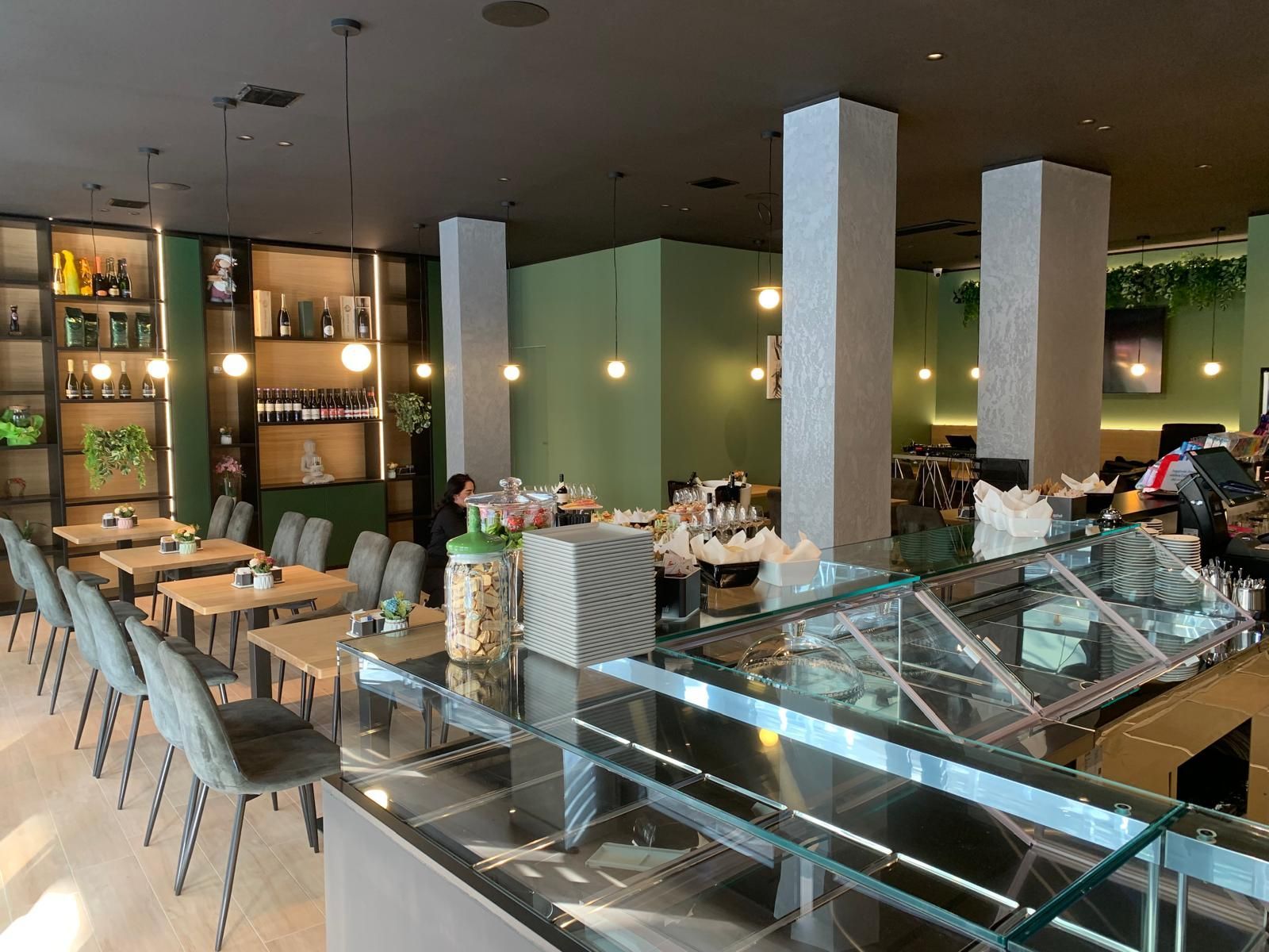 Un ristorante con tavoli e sedie e bancone in vetro.