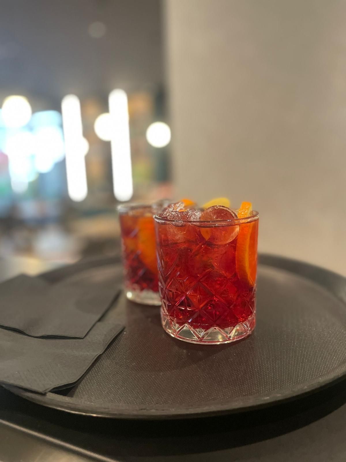 Due bicchieri di liquido rosso sono seduti su un vassoio nero.