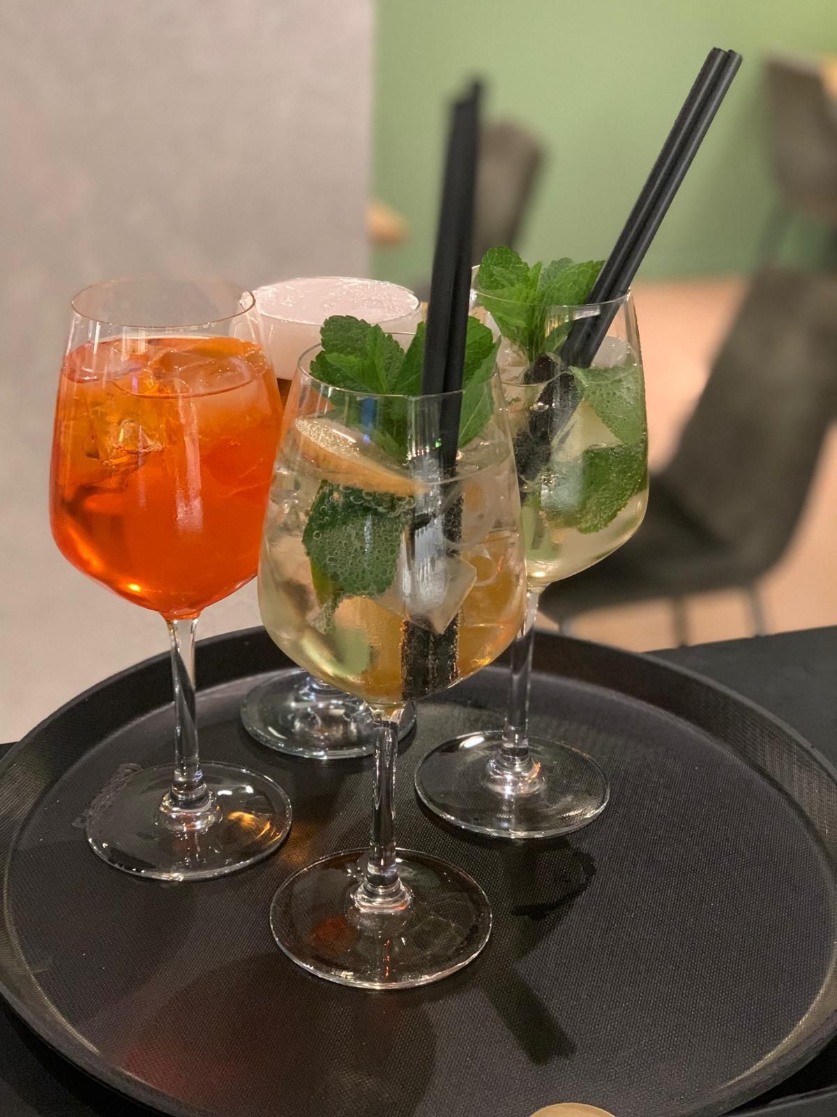 Tre bicchieri da vino riempiti con diversi tipi di bevande su un vassoio.