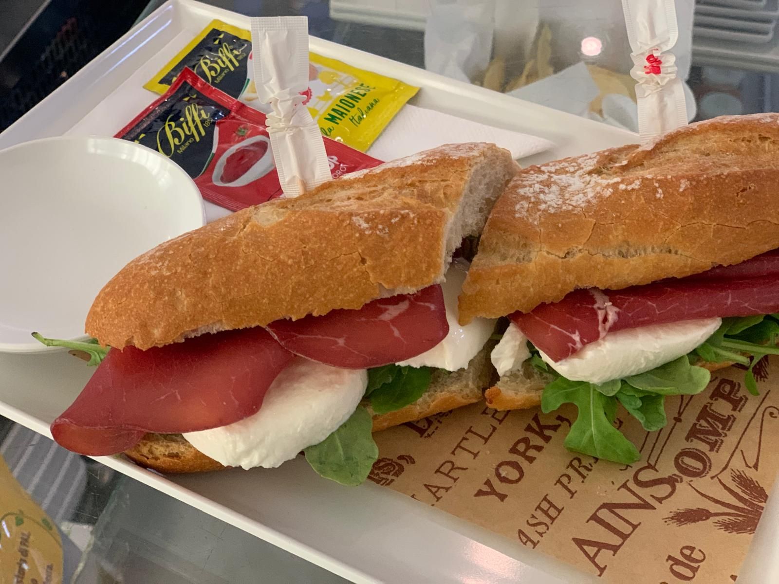 Un panino con carne e formaggio è su un piatto bianco.