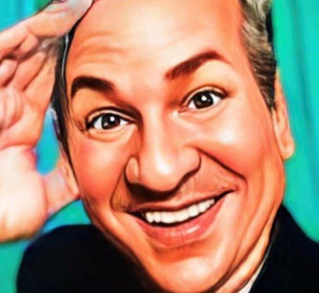 A man in a suit is smiling with his hand on his head