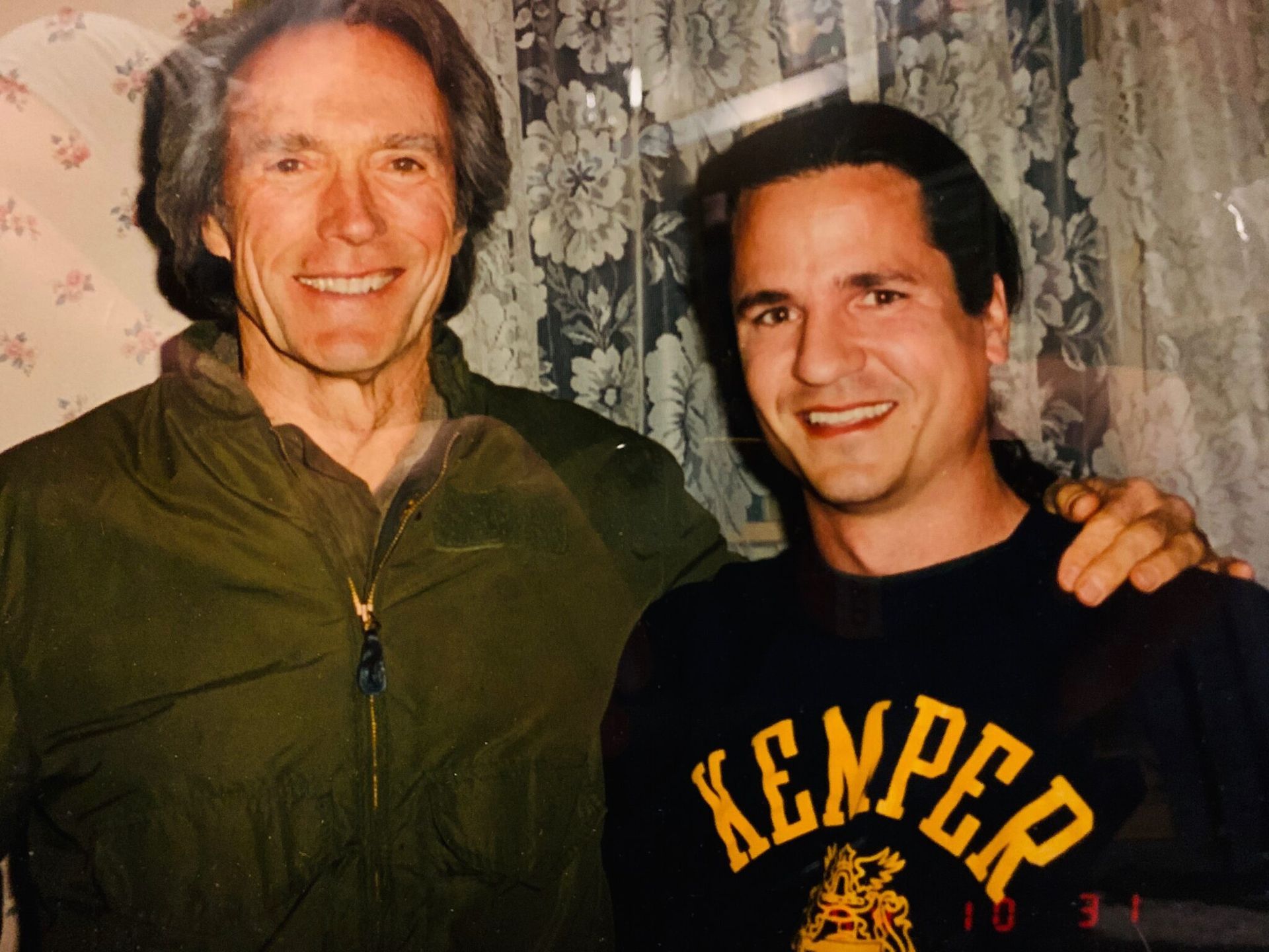 A man wearing a kemper shirt stands next to another man