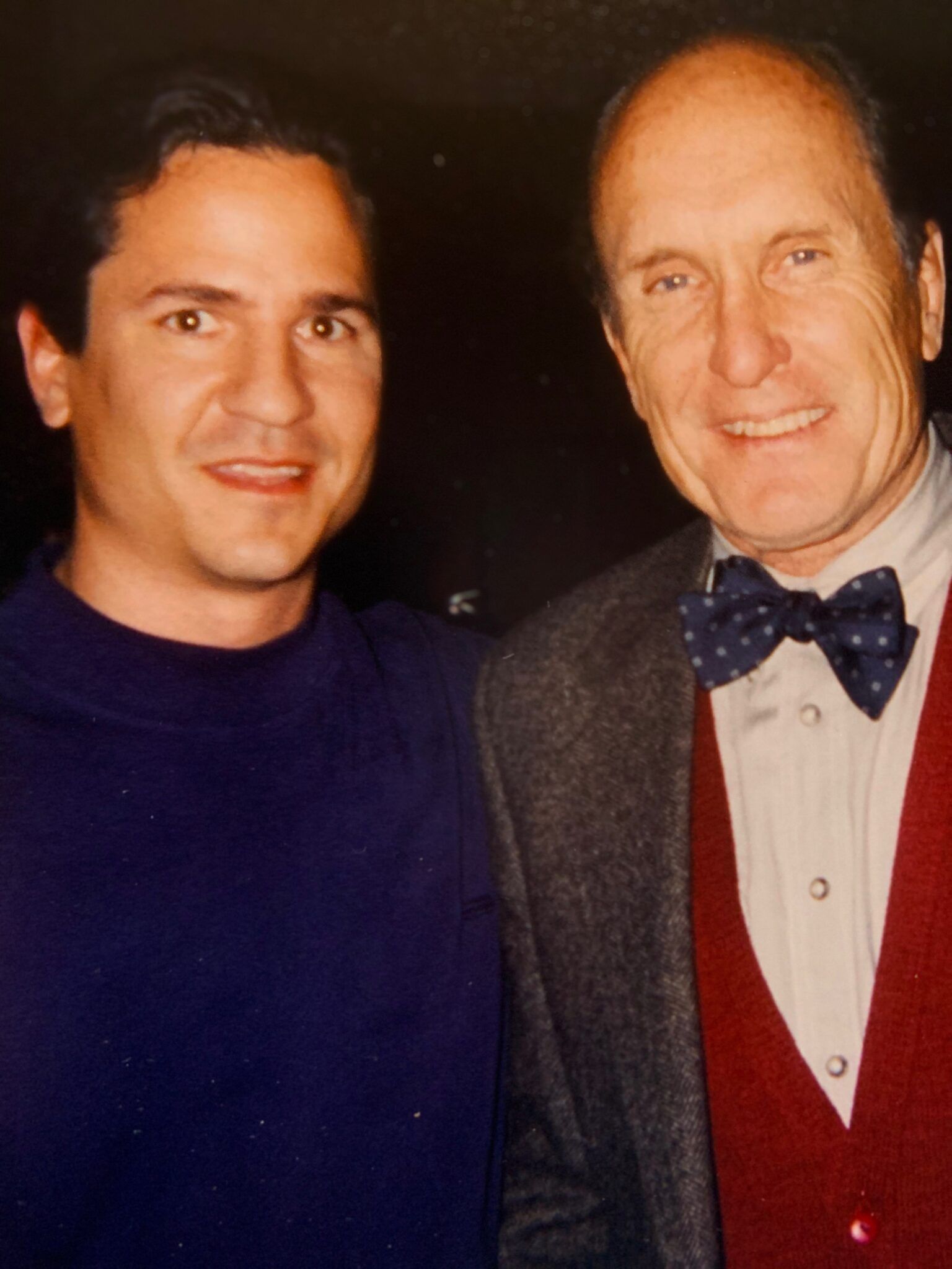 Two men are posing for a picture and one is wearing a bow tie
