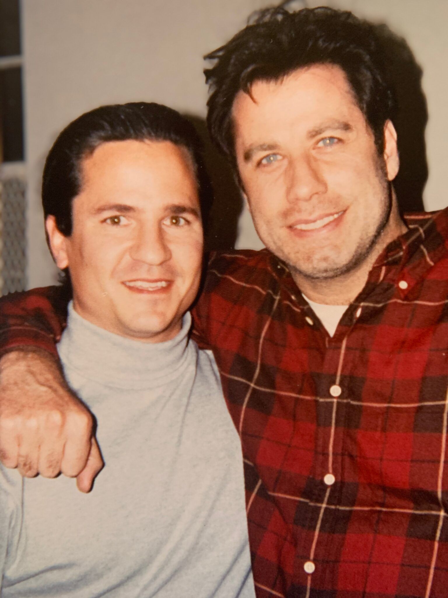 Two men are posing for a picture and one is wearing a plaid shirt