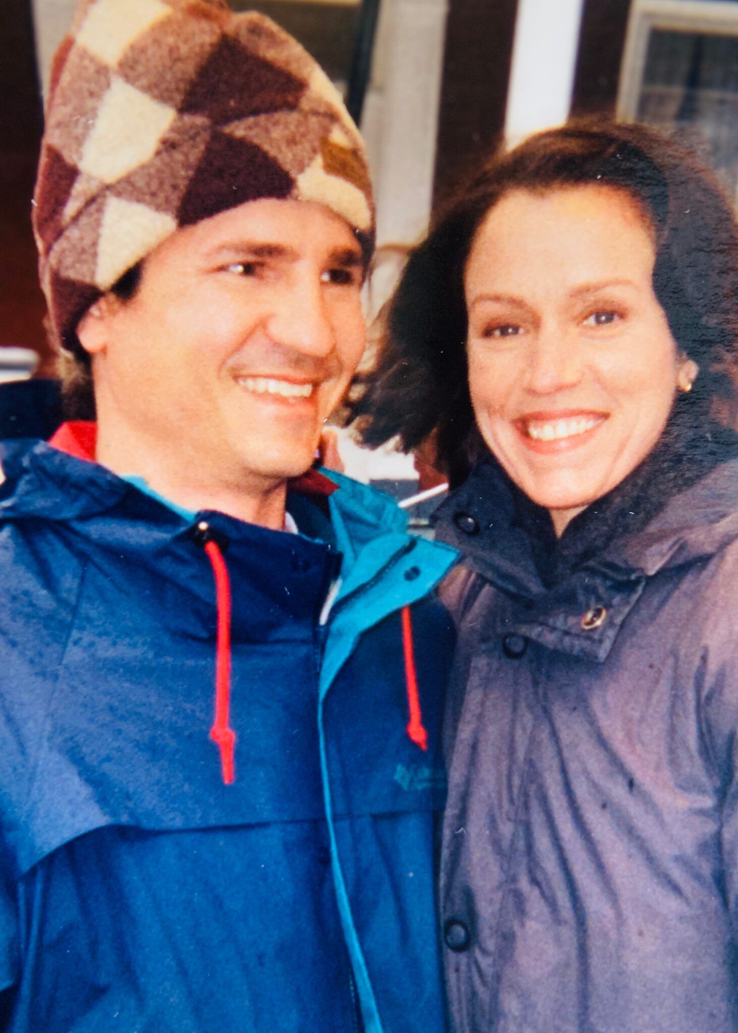 A man and a woman are posing for a picture and the man is wearing a hat