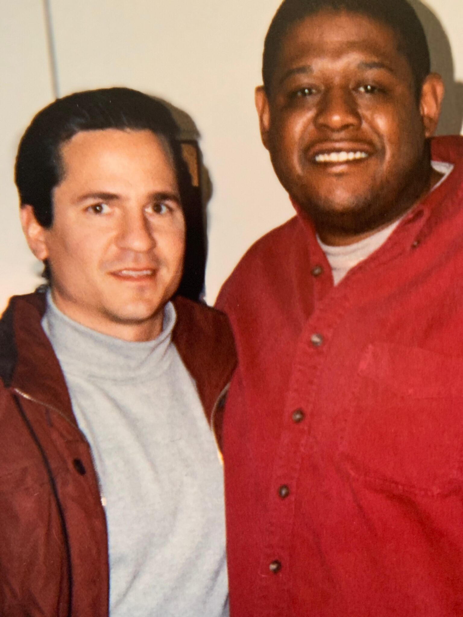 Two men are posing for a picture and one is wearing a red shirt