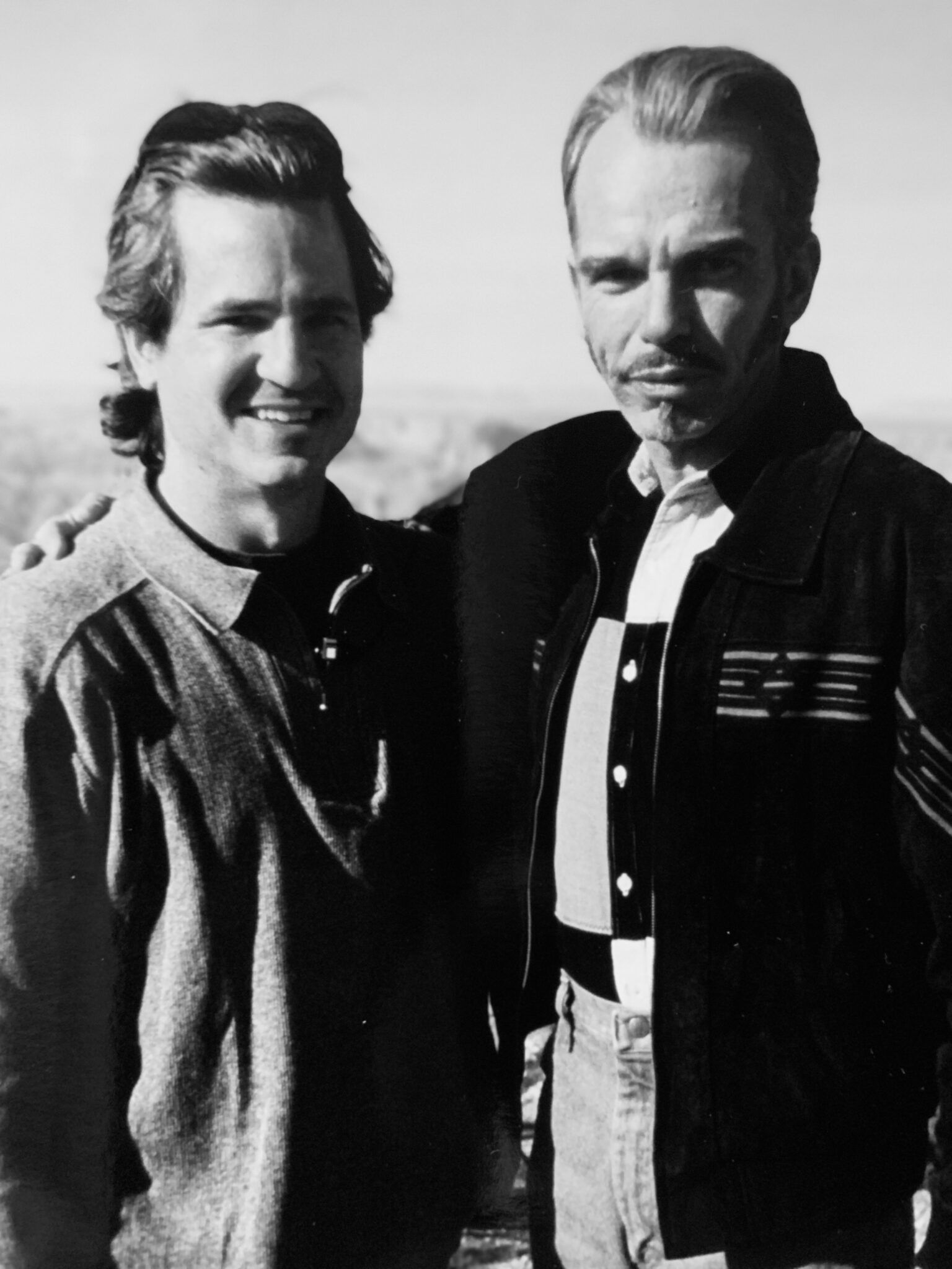 Two men standing next to each other with one wearing a jacket that says pee
