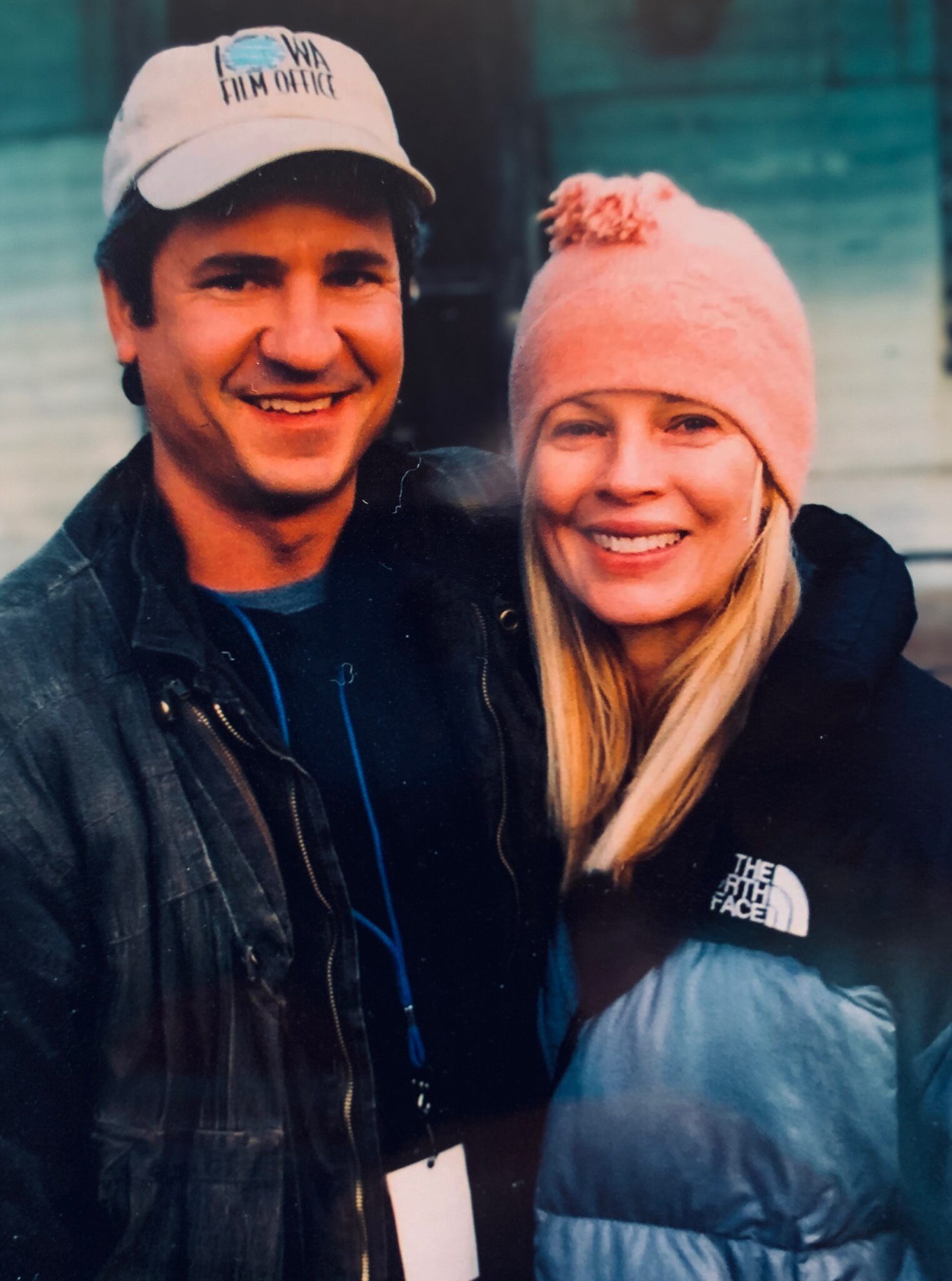 A man and a woman are posing for a picture and the woman is wearing a pink hat
