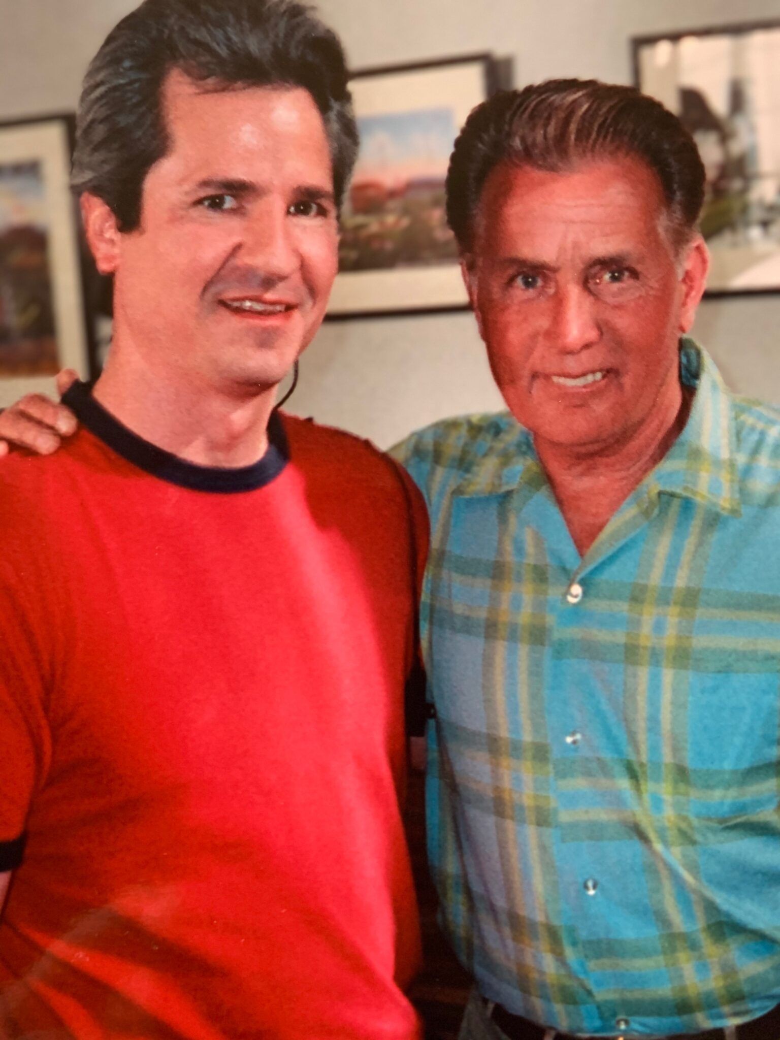 Two men are posing for a picture together and one of them is wearing a red shirt.