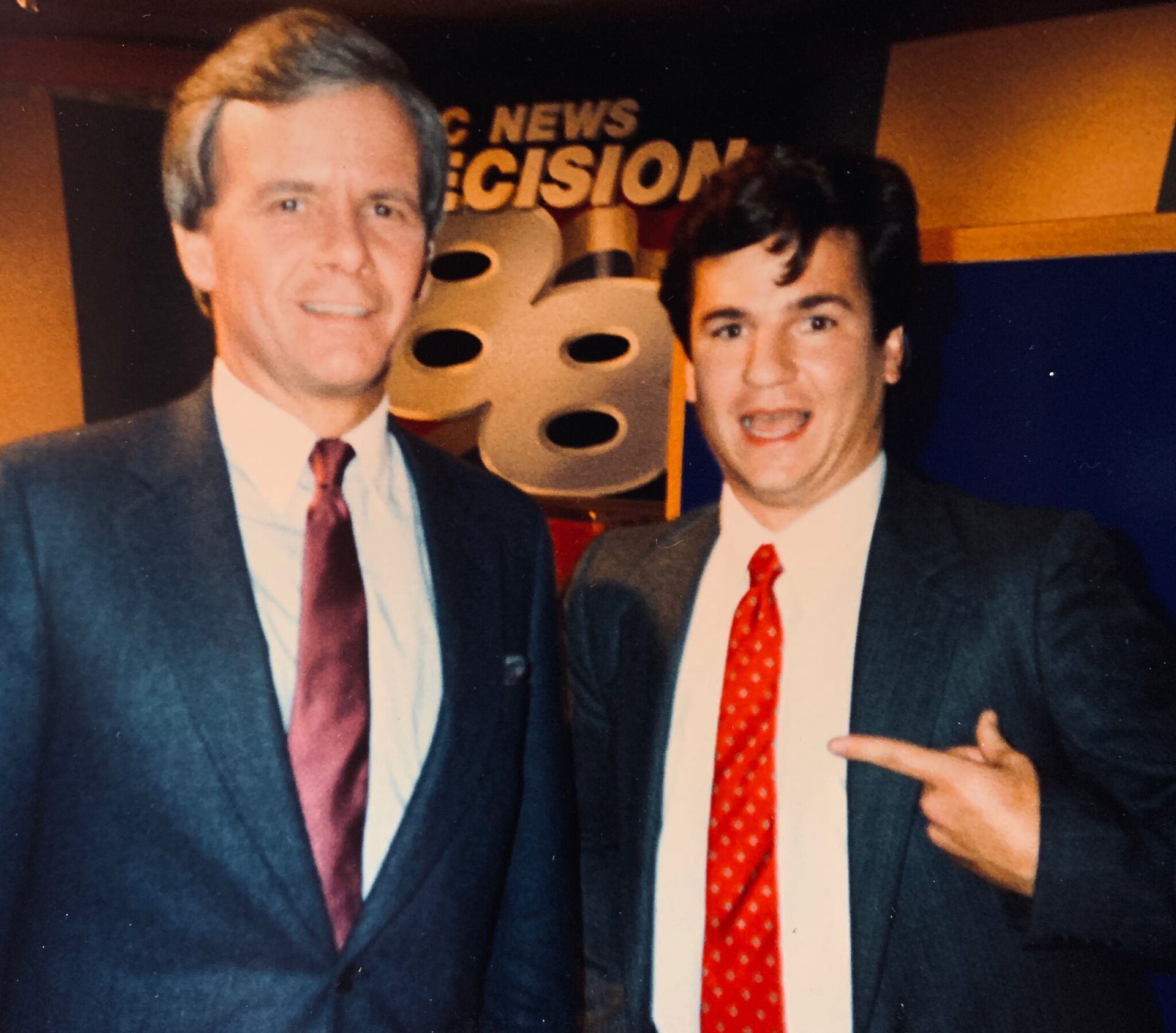 Two men standing in front of a sign that says news cision