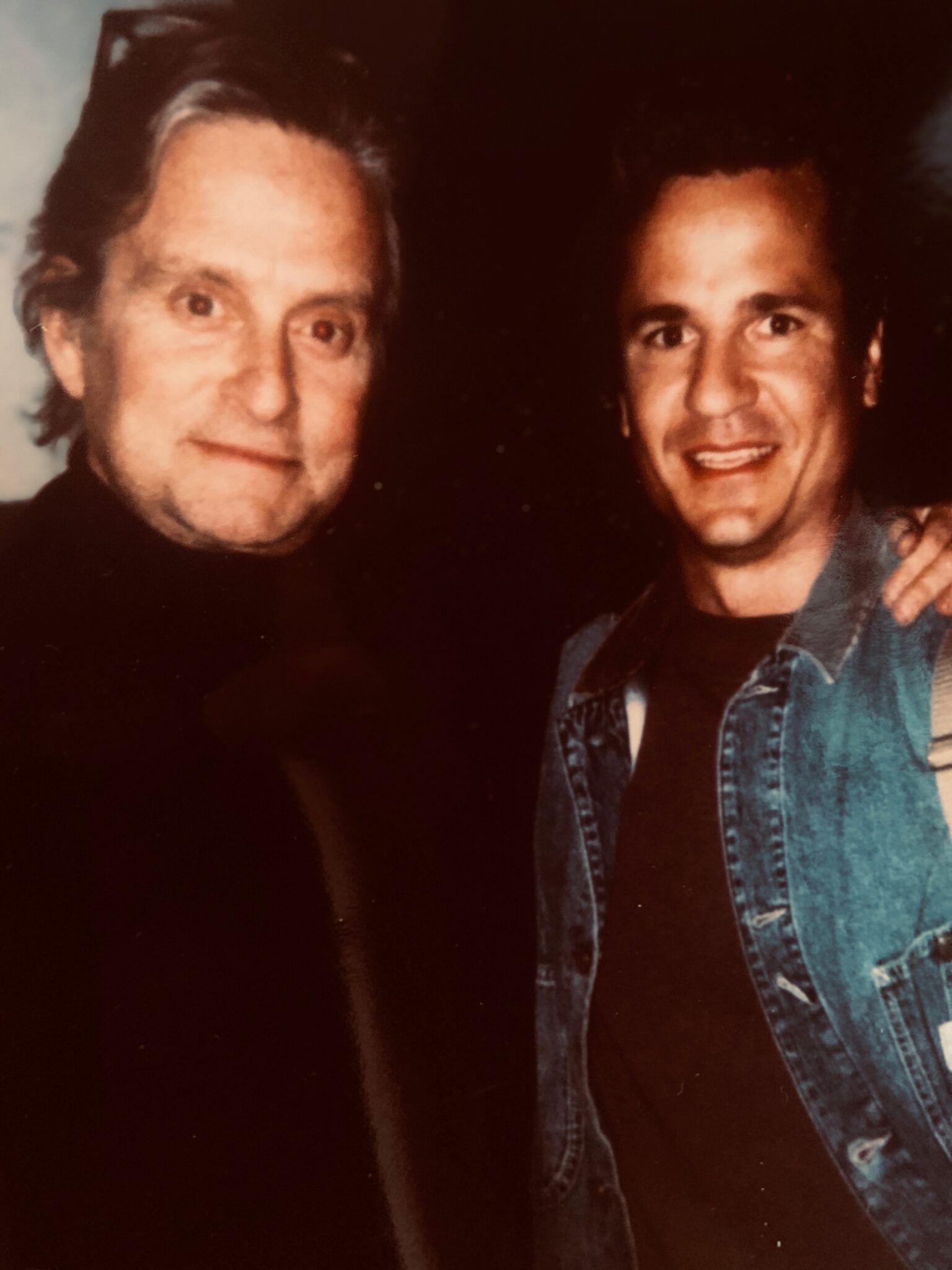 Two men are posing for a picture together and one of them is wearing a denim jacket.