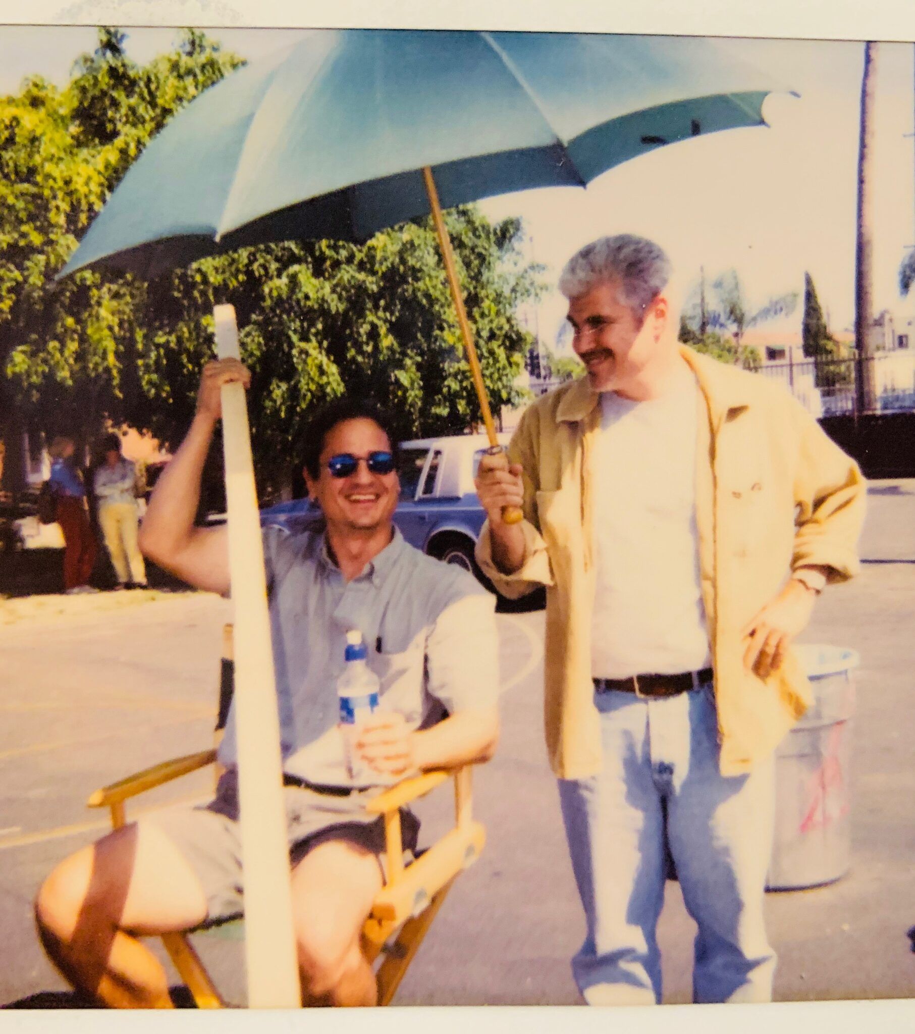 A man sitting in a director 's chair holding an umbrella