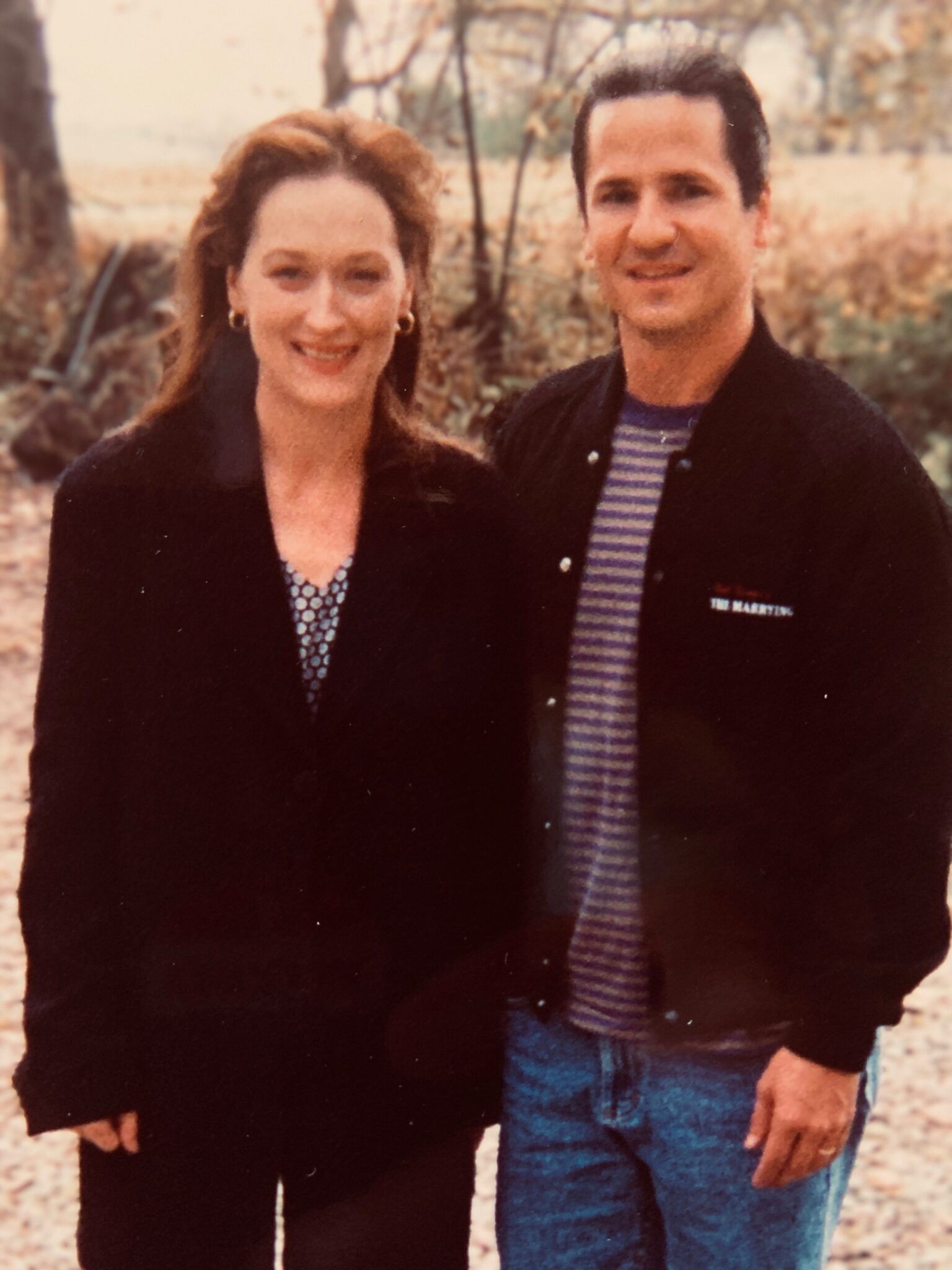 A man and a woman are posing for a picture in a field.