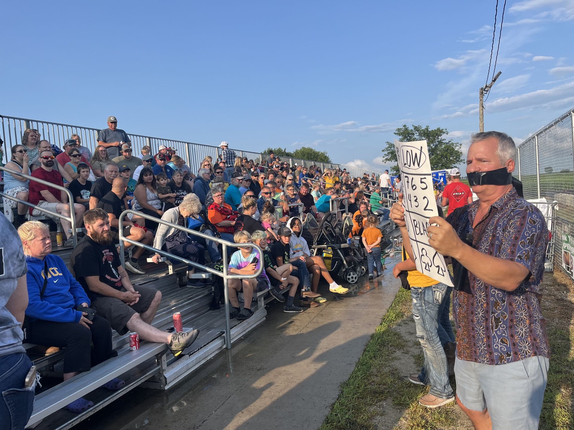 A man is standing in front of a crowd of people holding a sign.