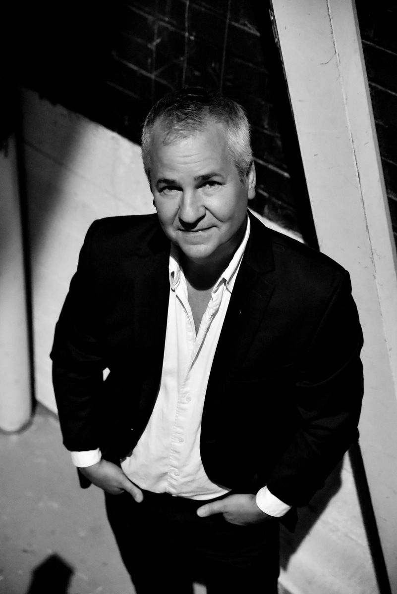 A man in a suit and white shirt is standing with his hands in his pockets.