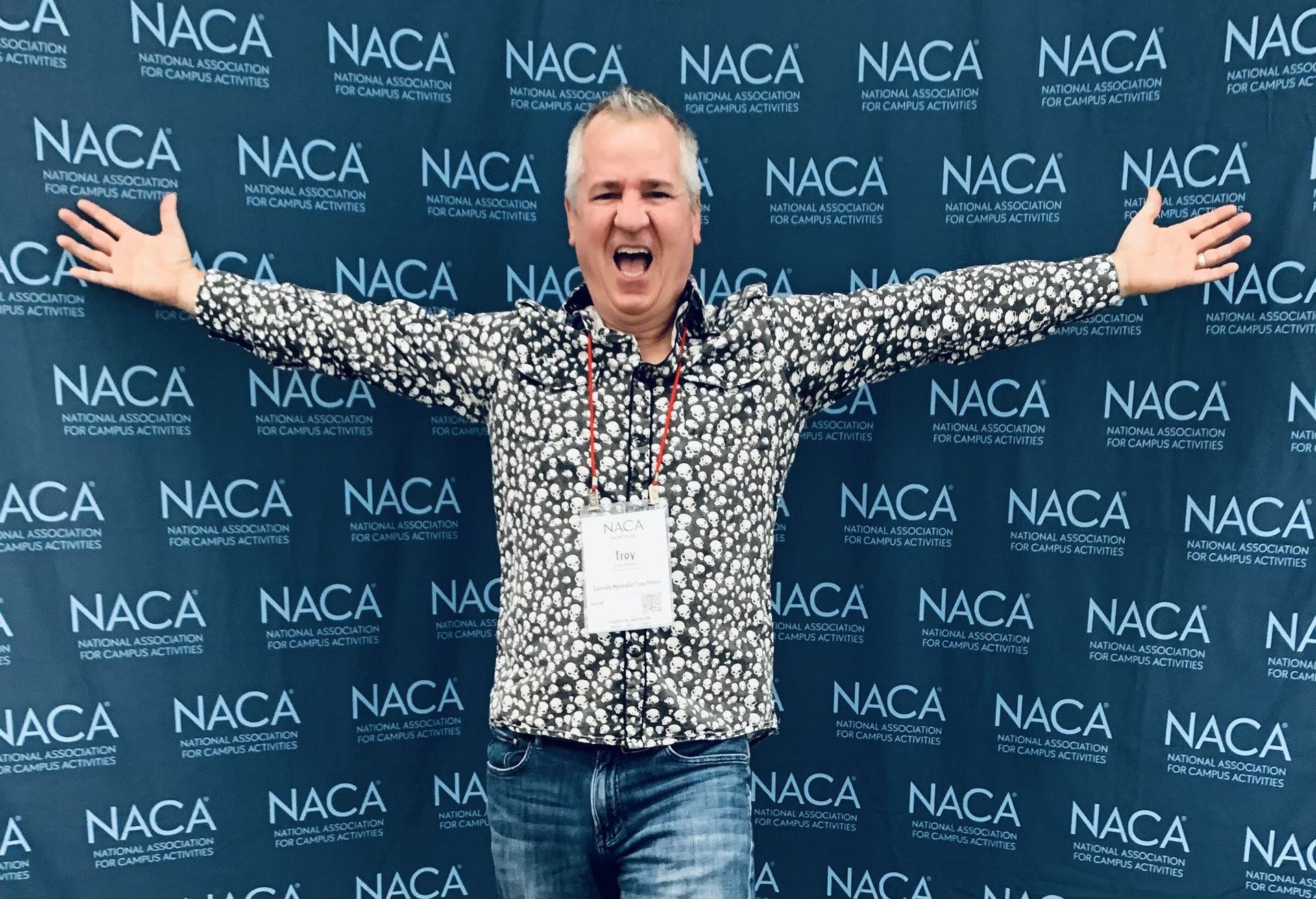 A man is standing in front of a wall that says naca