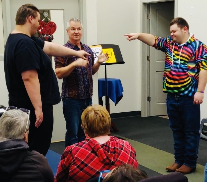 A man in a rainbow shirt is pointing at another man
