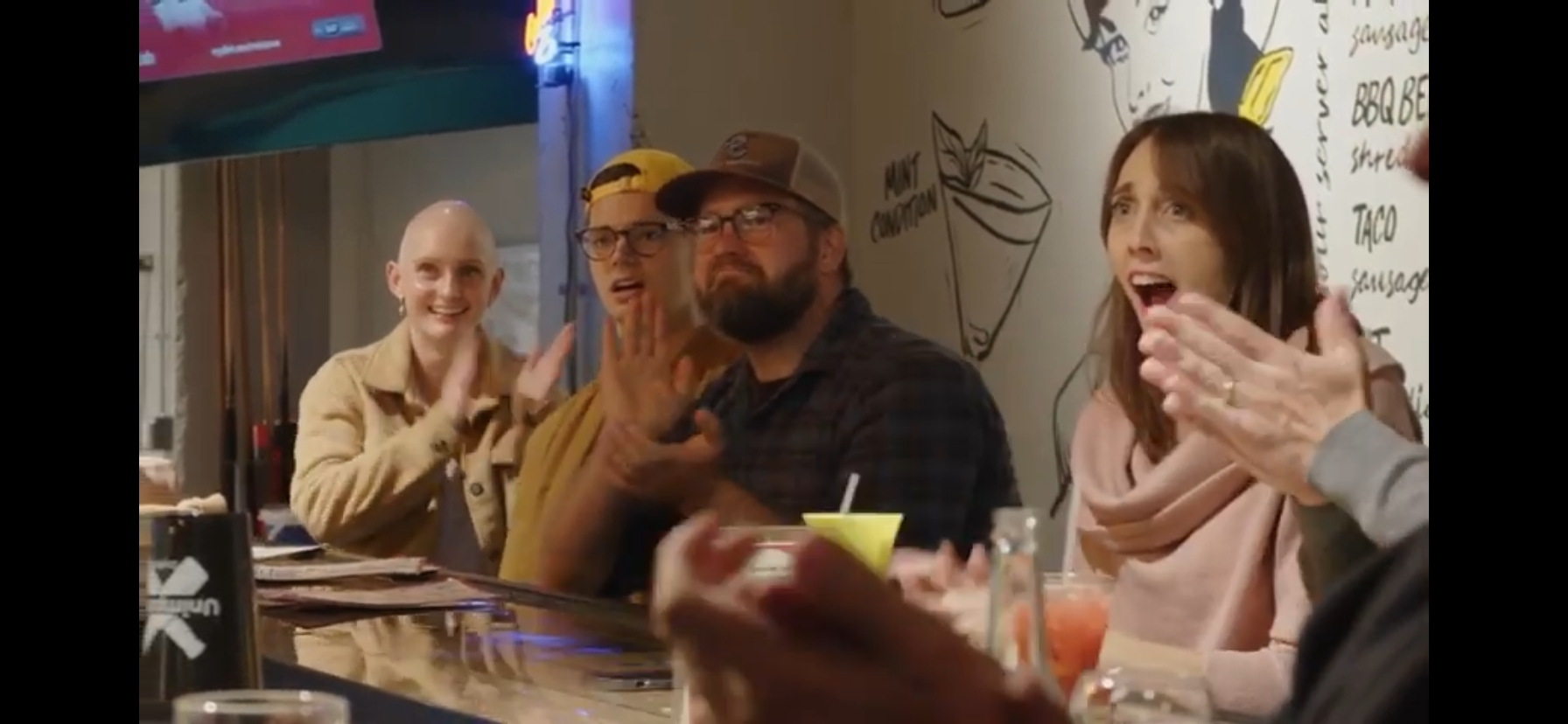 A group of people are sitting at a table in a restaurant applauding.