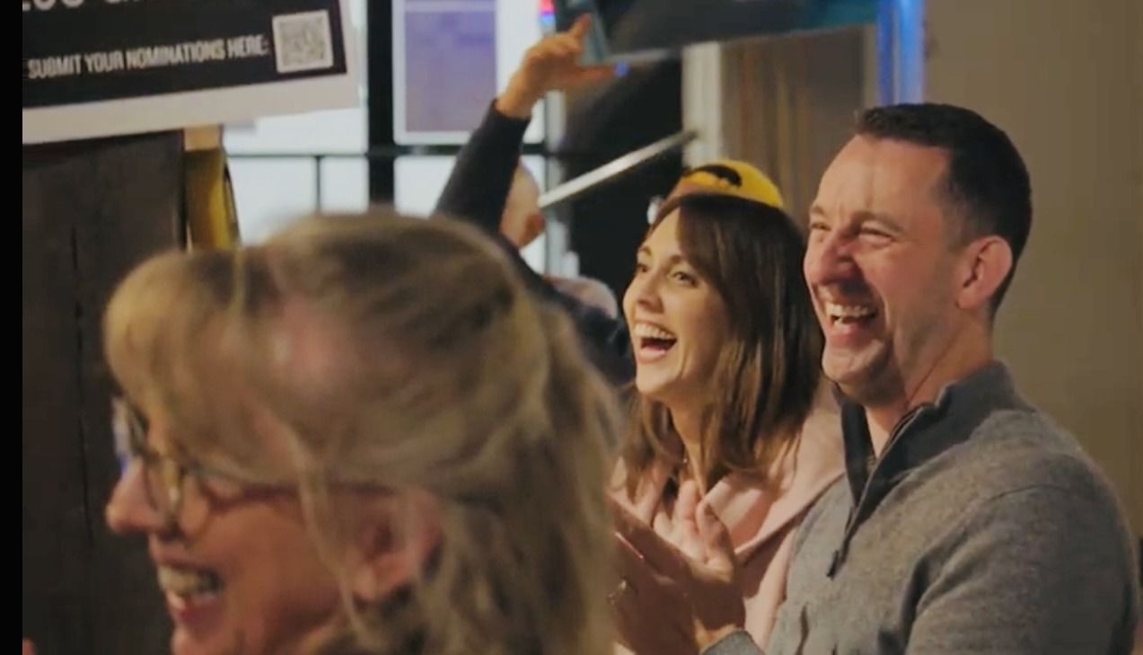 A group of people are laughing and clapping in a room.