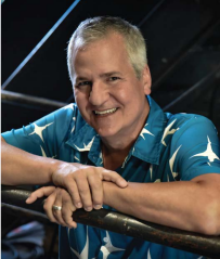 A man in a blue shirt is leaning on a railing