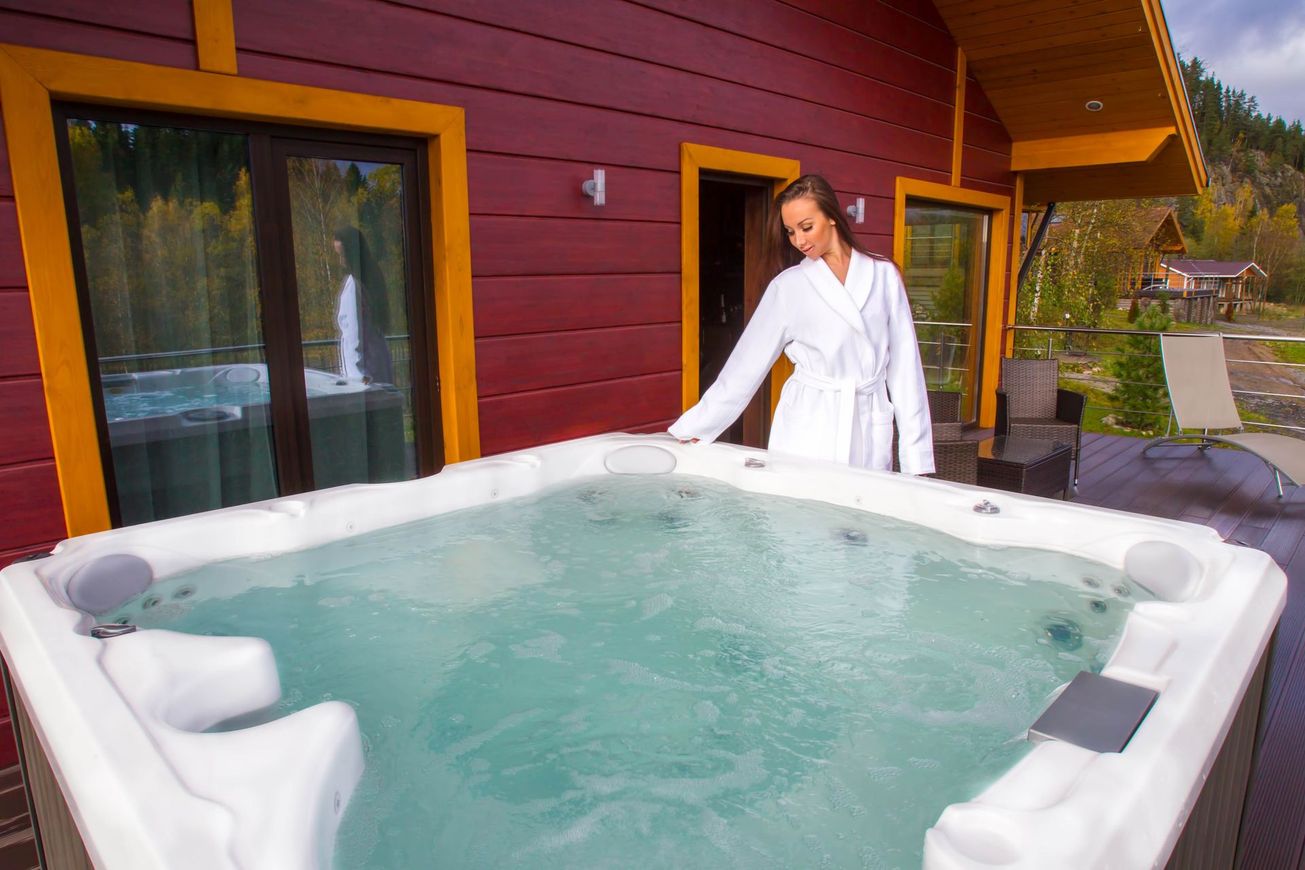 a woman in a bathrobe is standing next to a hot tub outside of a house