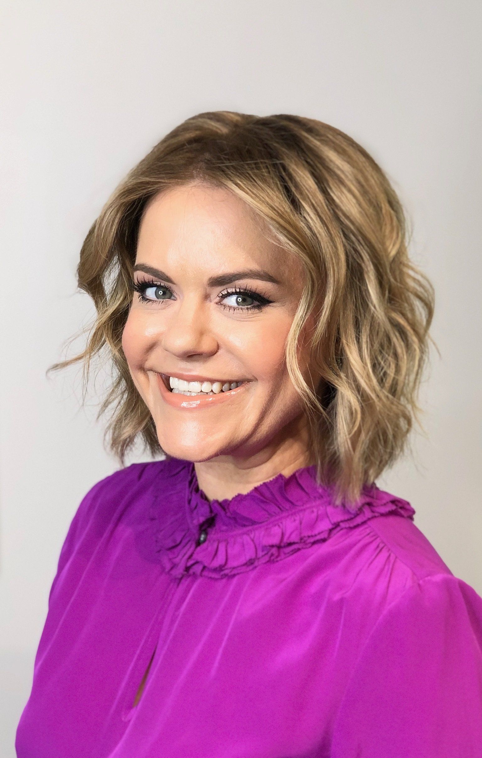 Blond business woman with bob haircut and full highlights styled with curled hair